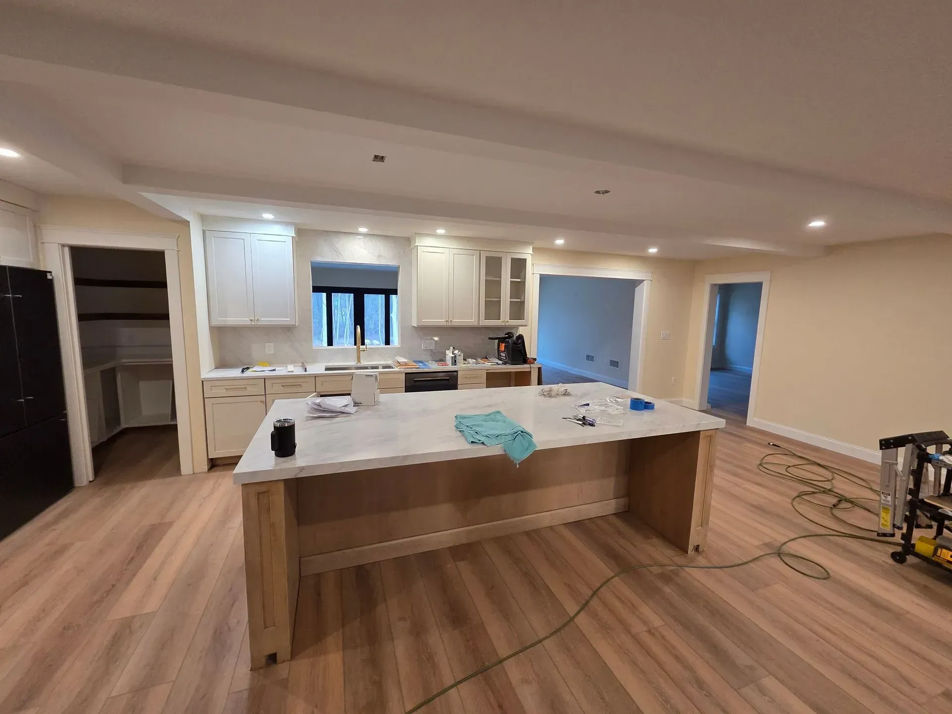 Newly renovated kitchen with a large island, white cabinets, and light wood flooring.
