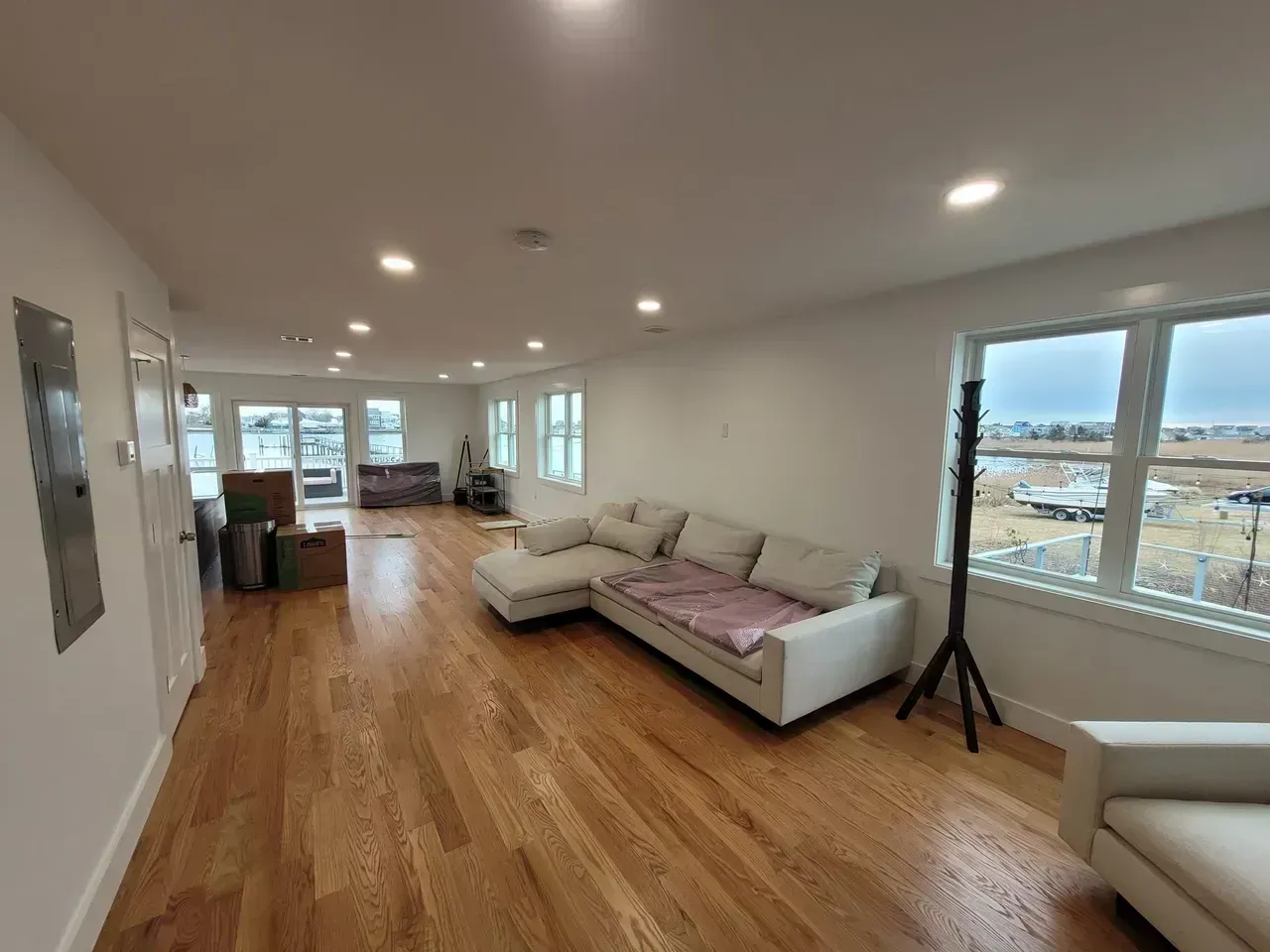 Spacious living room with hardwood floors, white walls, and a large sectional sofa near windows.