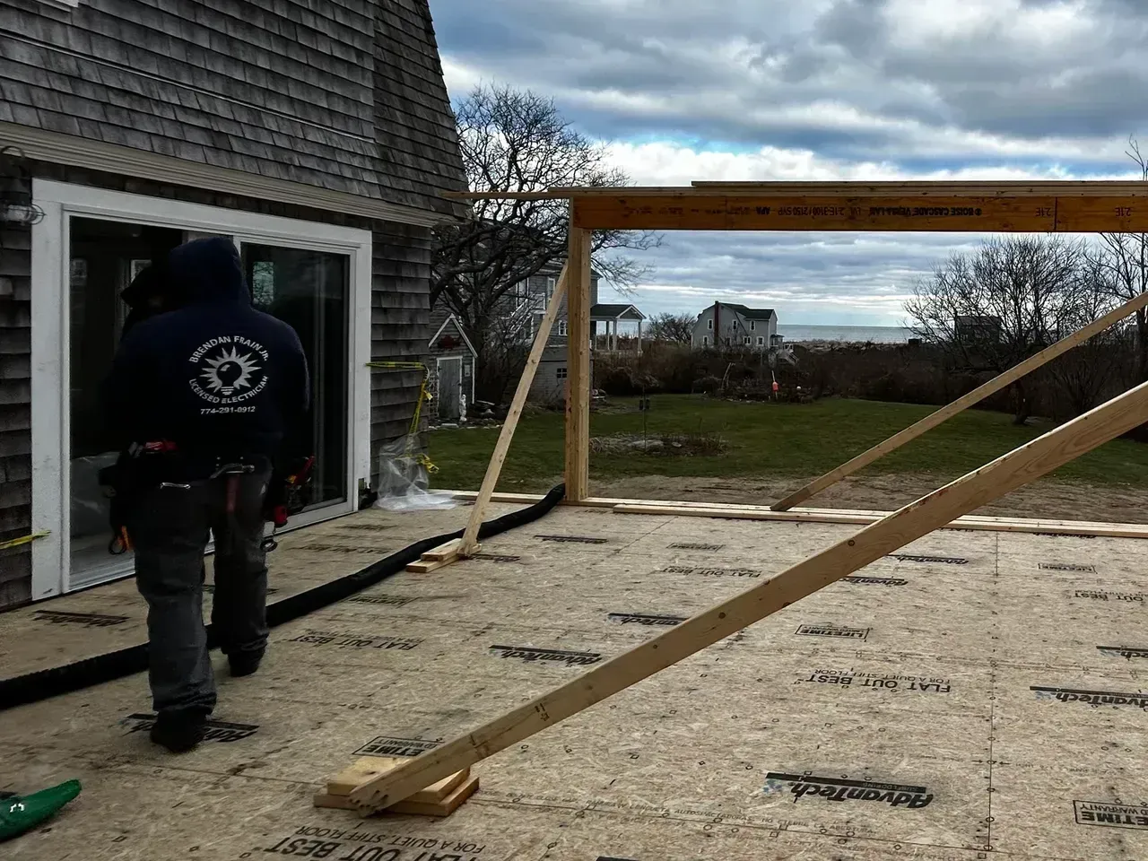 Construction worker near house with sliding door and framed structure.