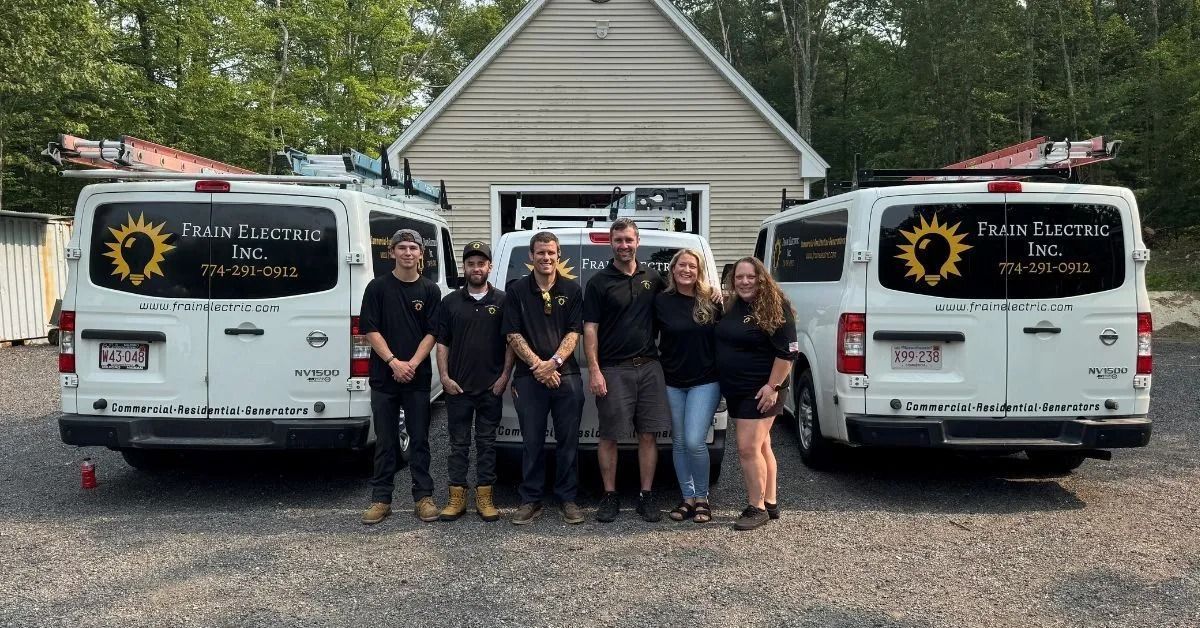 Group of people in front of two white vans with logo, standing in front of a building.