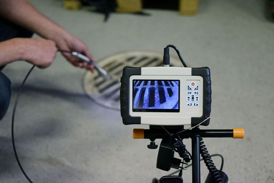 Hand holding a cable beside a monitor showing a striped test pattern on a stand