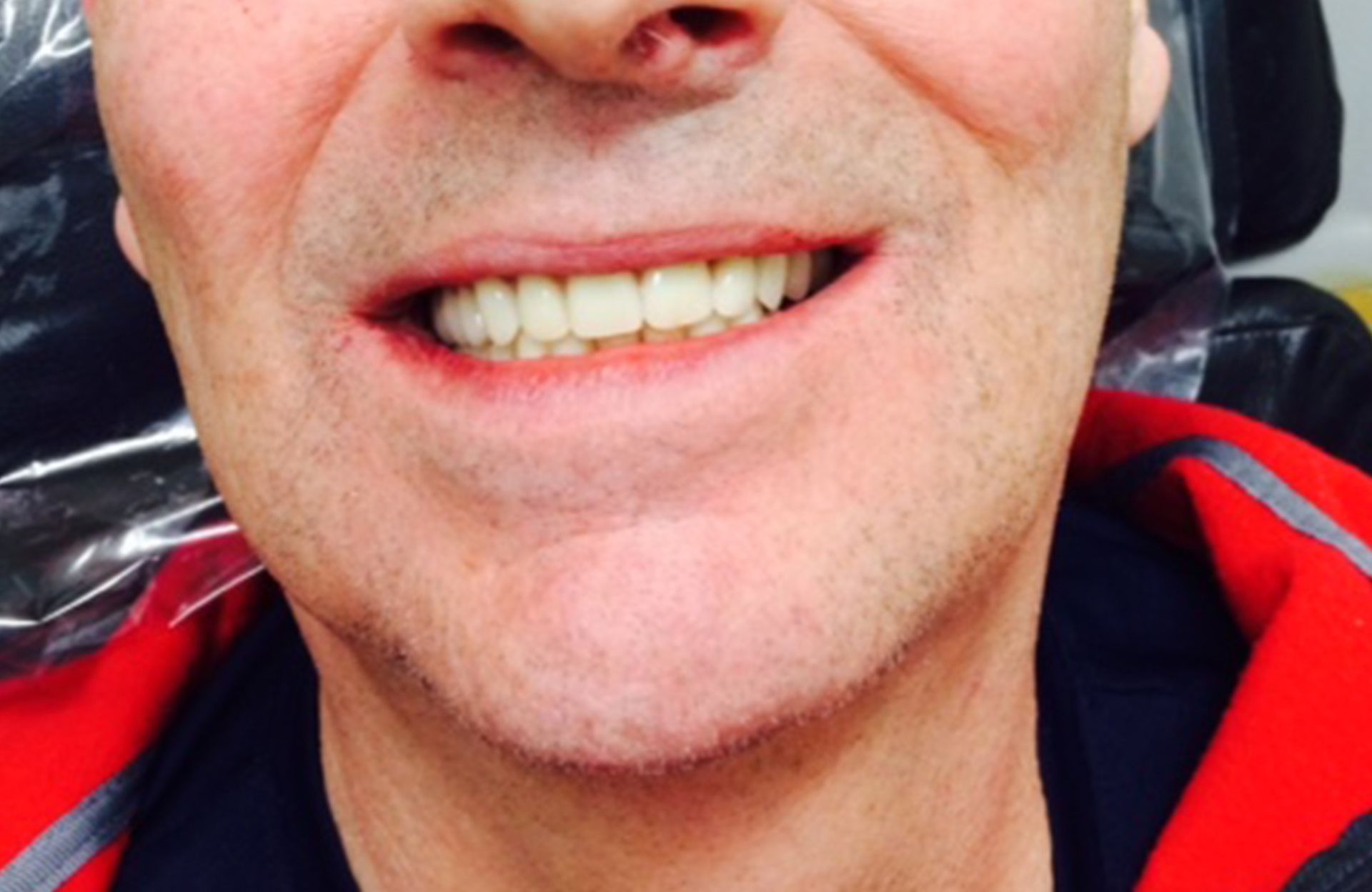 Close-up of a smiling person wearing a red and black jacket and a nose ring