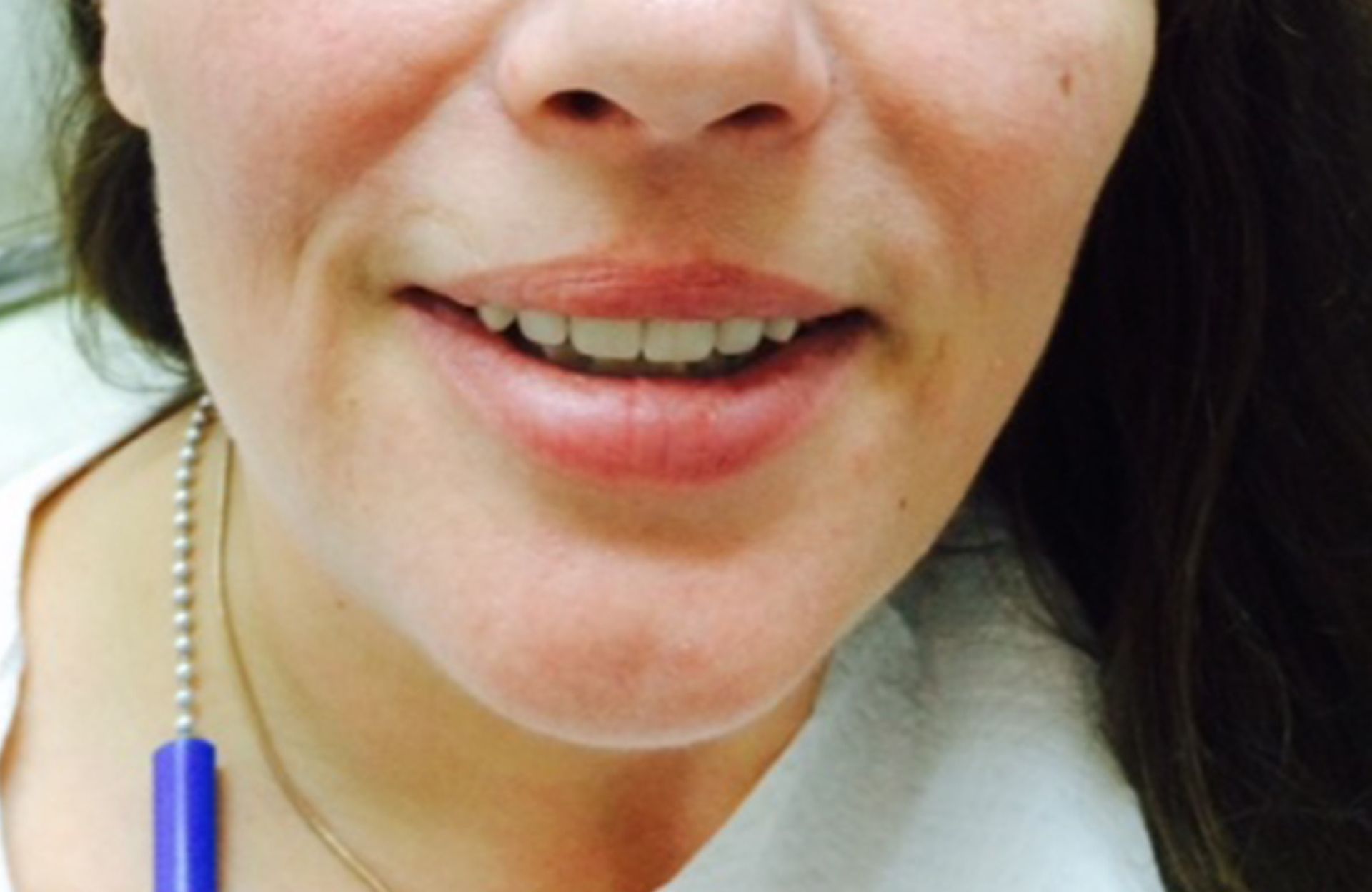 Close-up of a smiling person speaking, with a blue pen beside their cheek