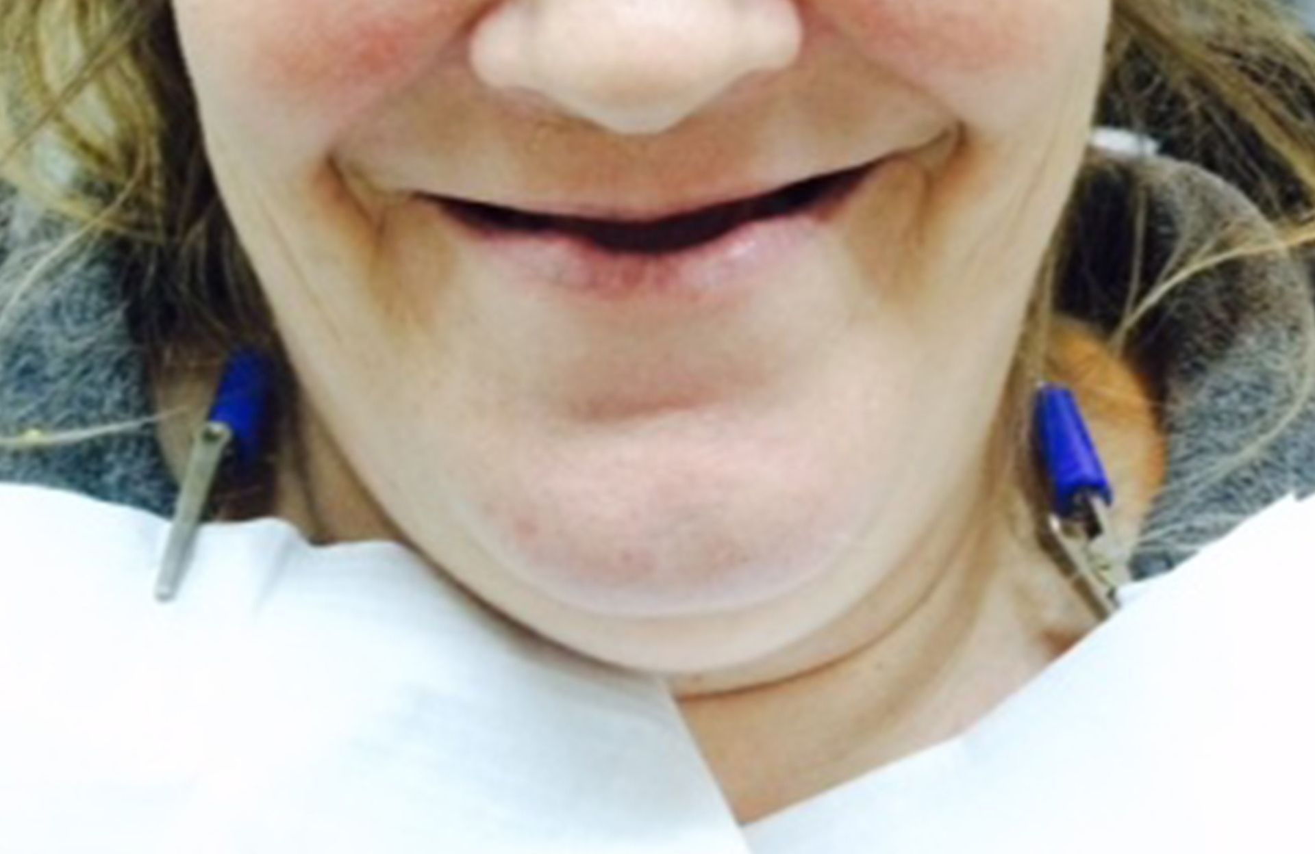Close-up of a smiling person wearing blue earrings and a white top