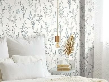 Bedroom with floral wallpaper, white bedding, hanging light, and gold leaf decor on a small table.