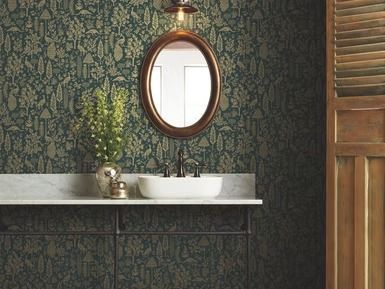 Bathroom with green wallpaper, oval mirror, white sink, and brown cabinet.
