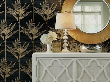 White console table with lamp, mirror, and vase against patterned wallpaper.