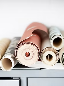 Rolled wallpaper samples in various colors, stacked on a shelf.