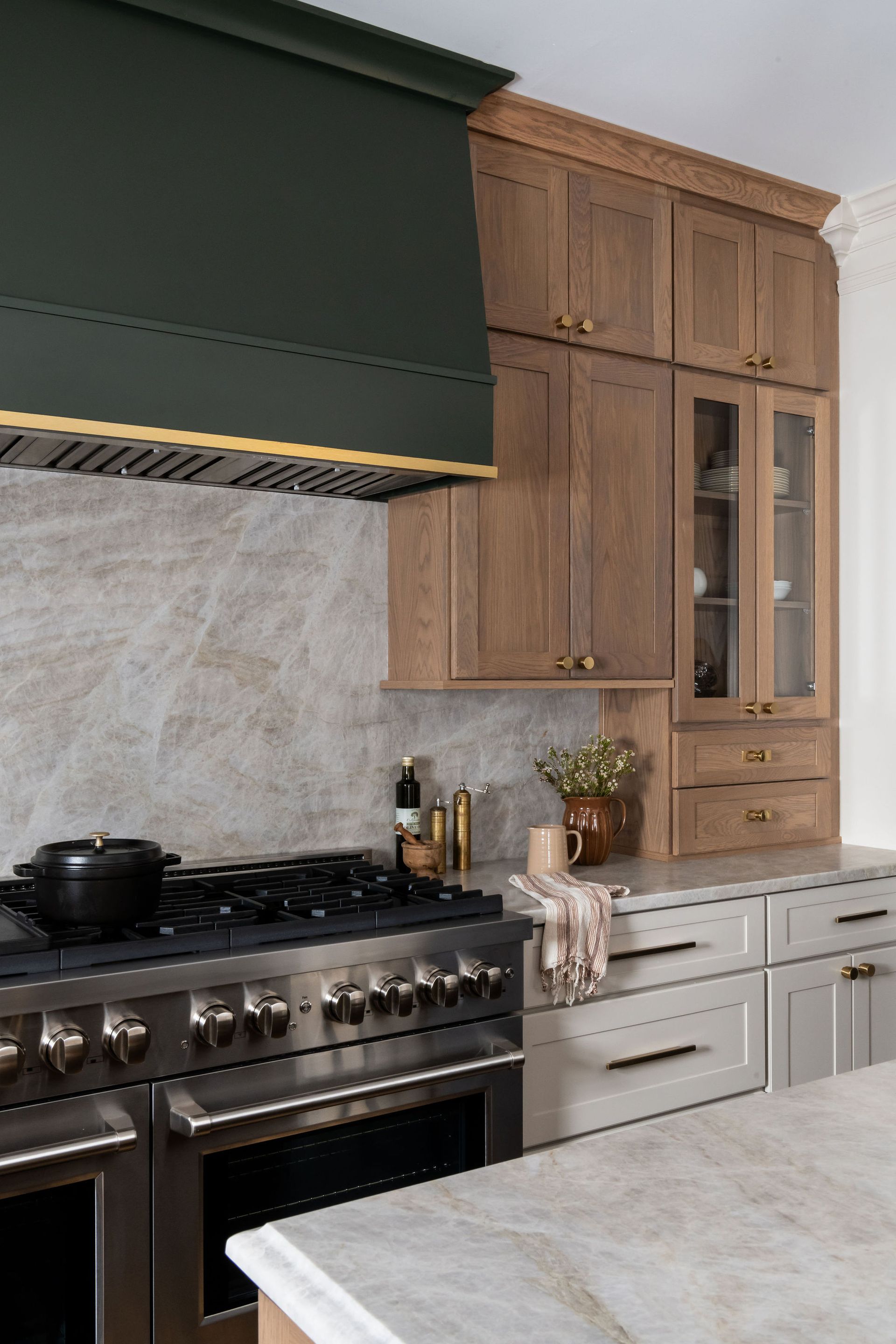 Kitchen with a dark green range hood, wooden cabinets, and a stainless steel oven.