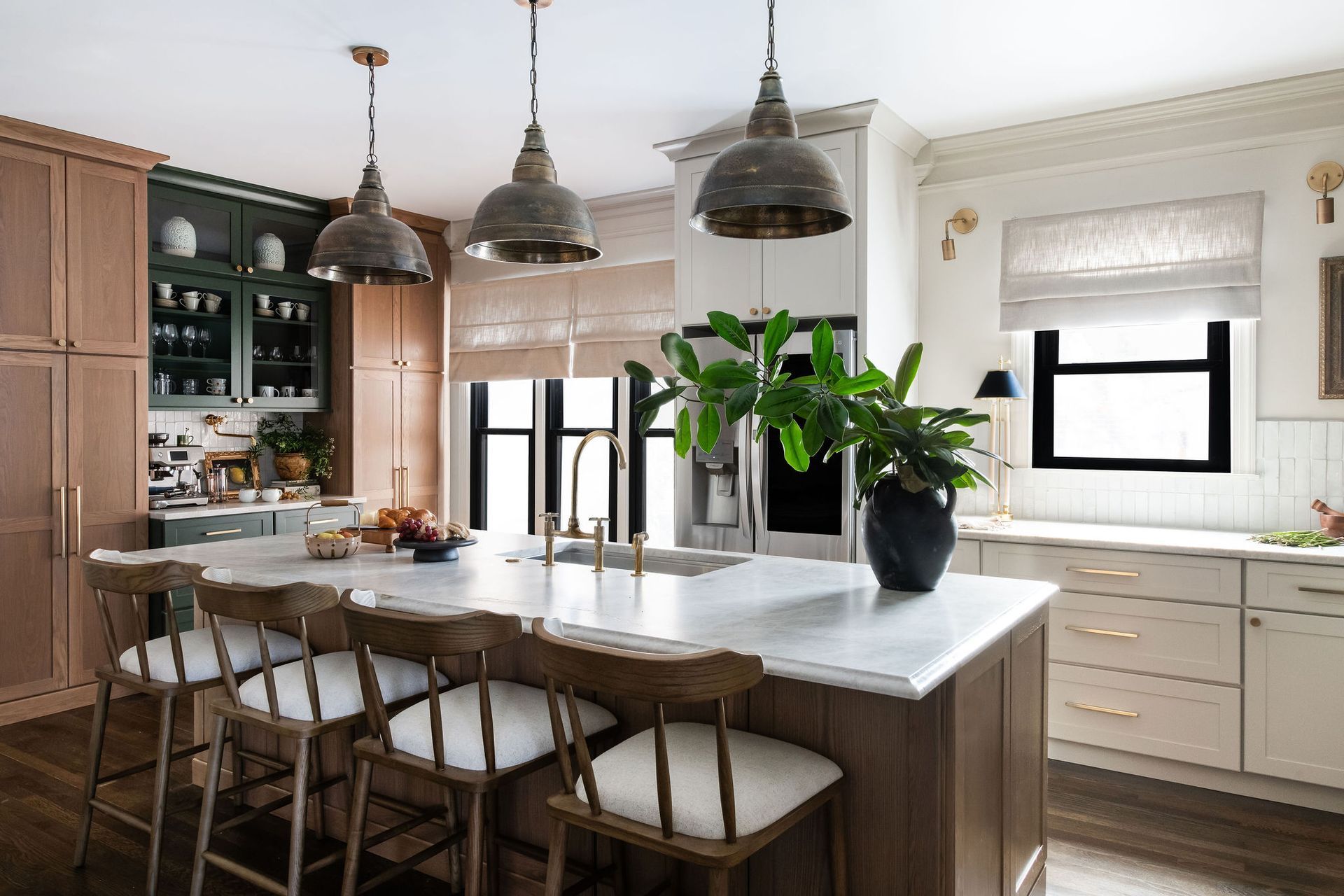 A modern kitchen with wooden cabinets, marble island, pendant lights, and bar stools.