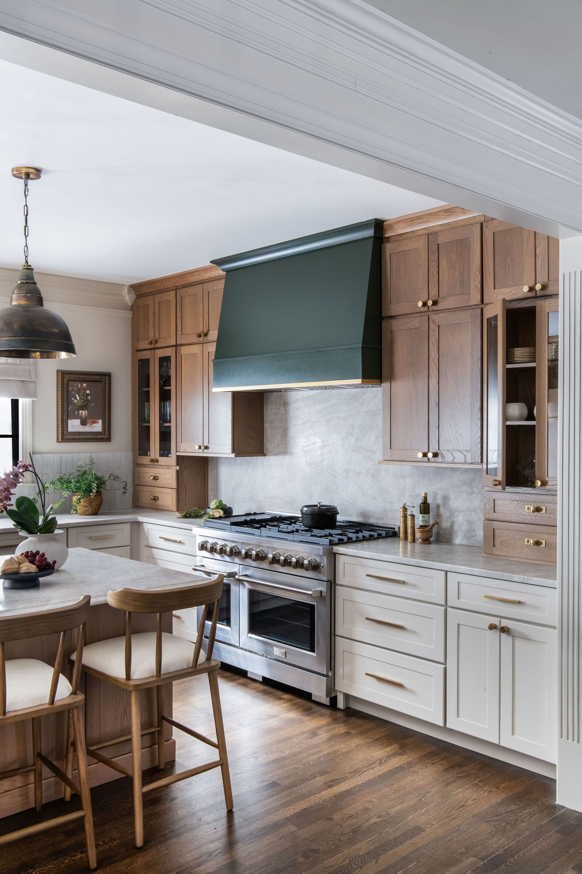 A kitchen with light wood cabinets, white countertops, and a dark green range hood.