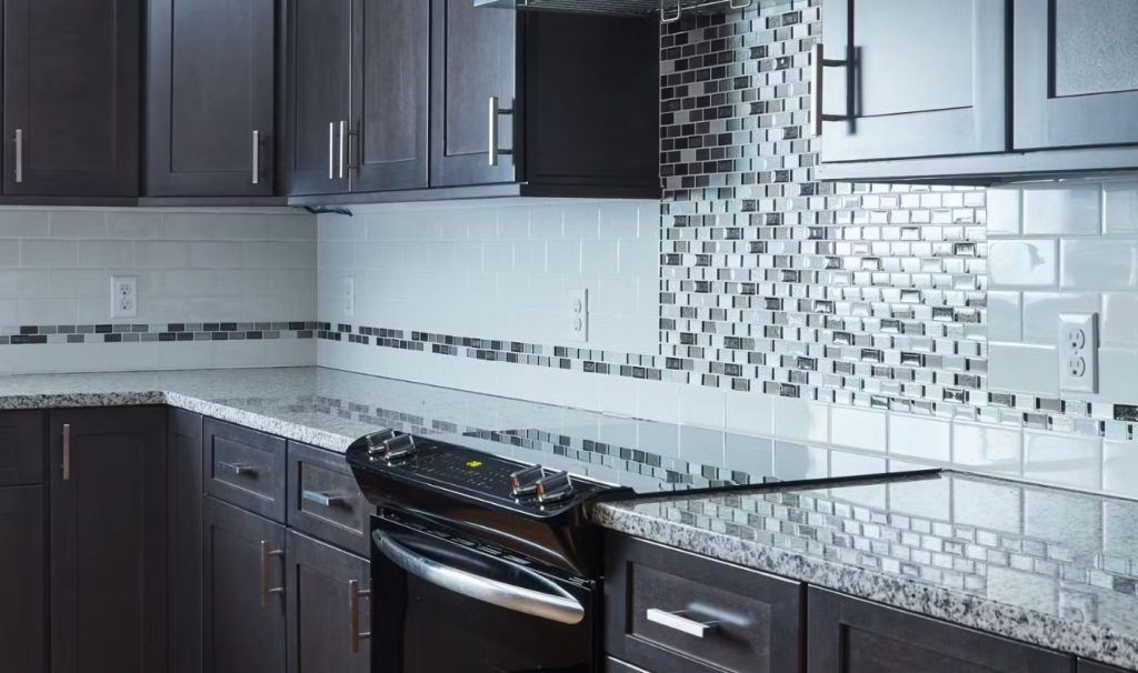 Kitchen with dark cabinets, granite countertop, and tile backsplash.