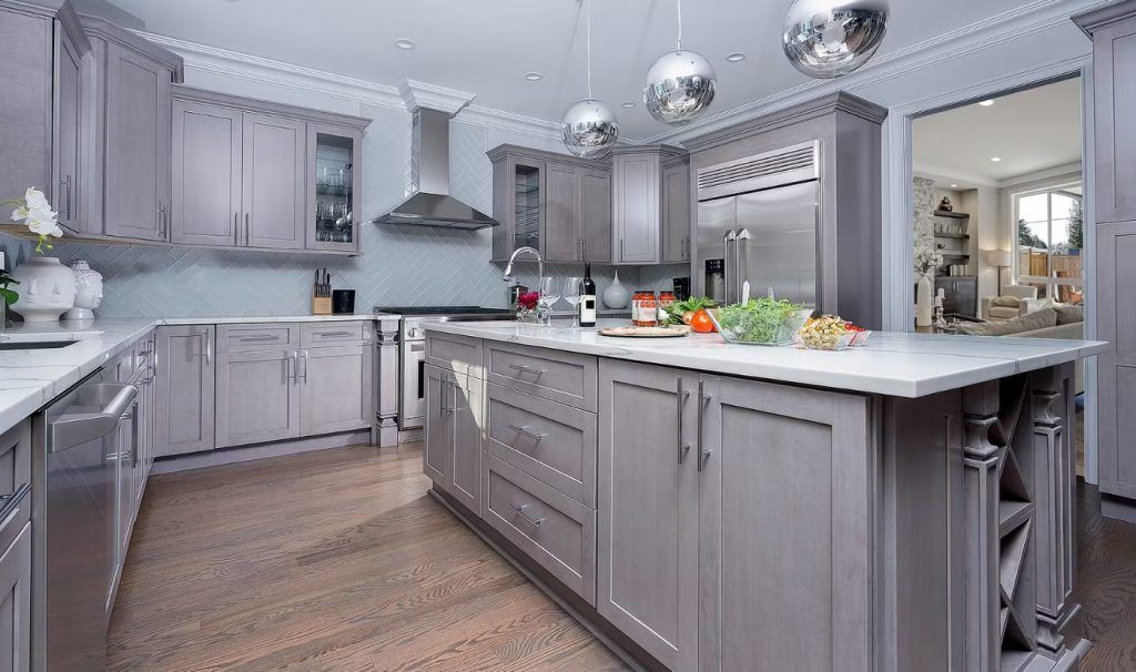 Gray kitchen with island, stainless steel appliances, white countertop, and hardwood floor.