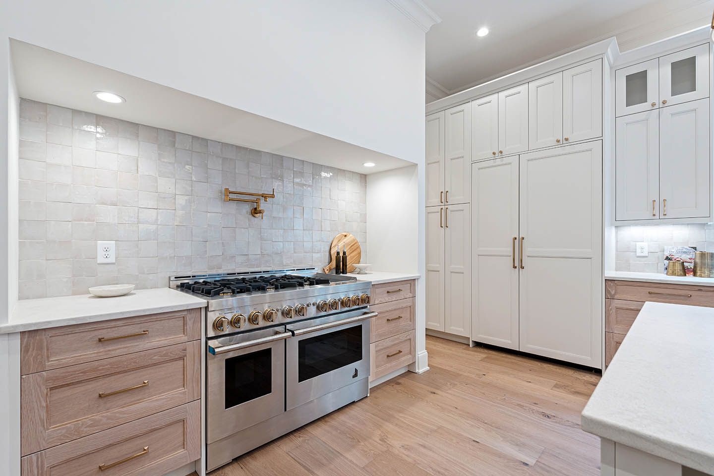 Modern kitchen with a stainless steel range, light wood cabinets, and white backsplash.