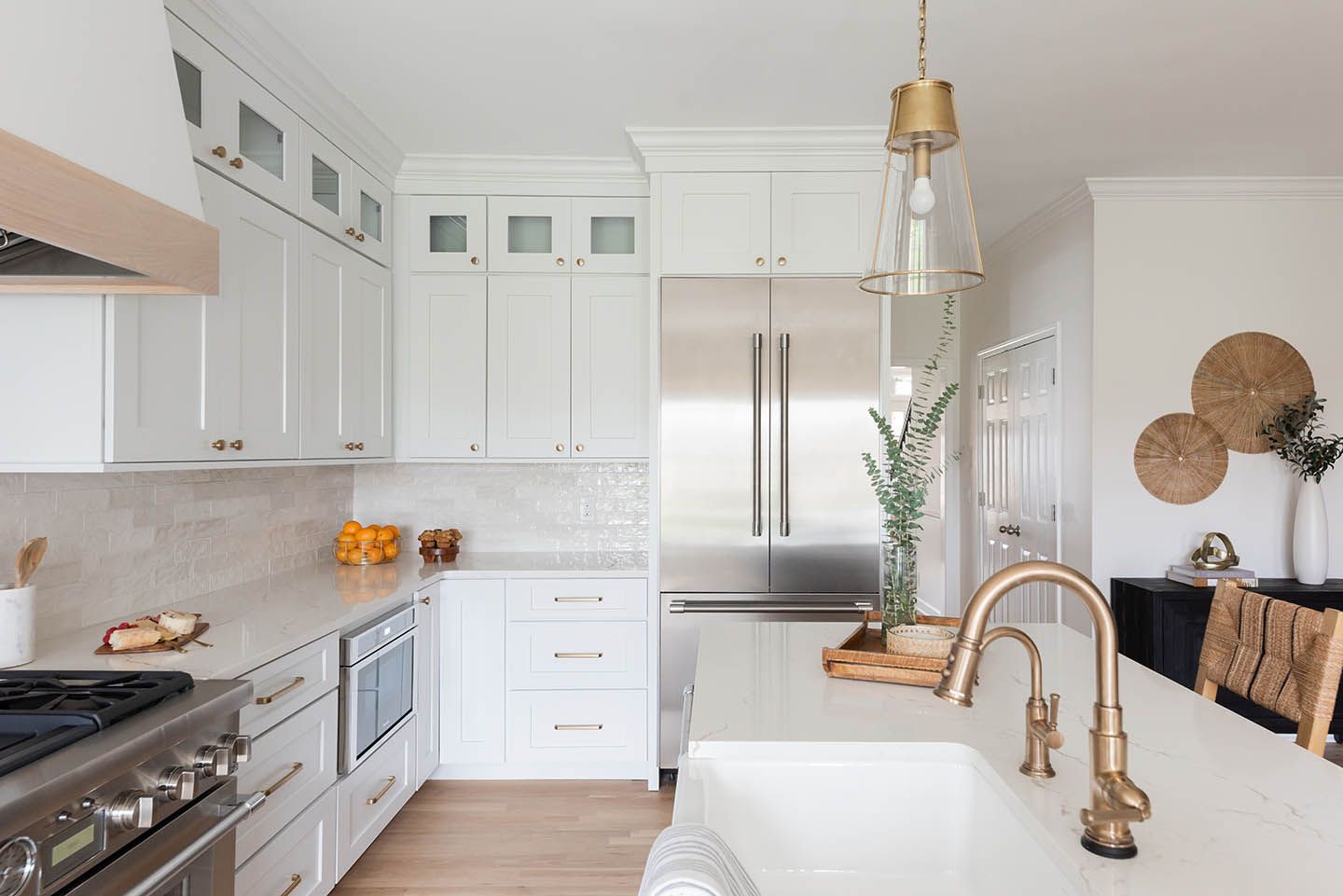 White kitchen with stainless steel appliances, marble countertops, and gold fixtures.