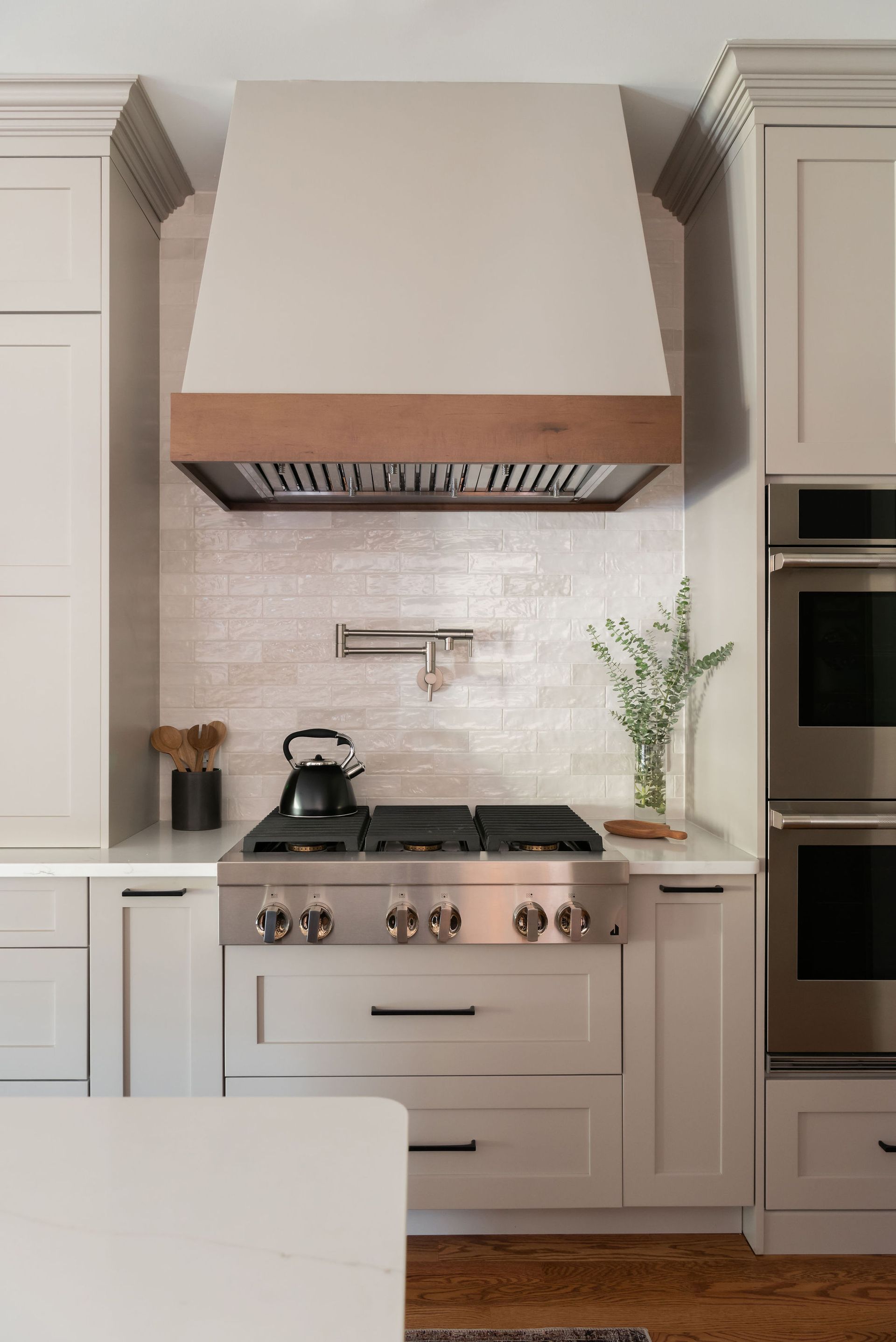 Kitchen with stainless steel stove, hood, and light-colored cabinetry.