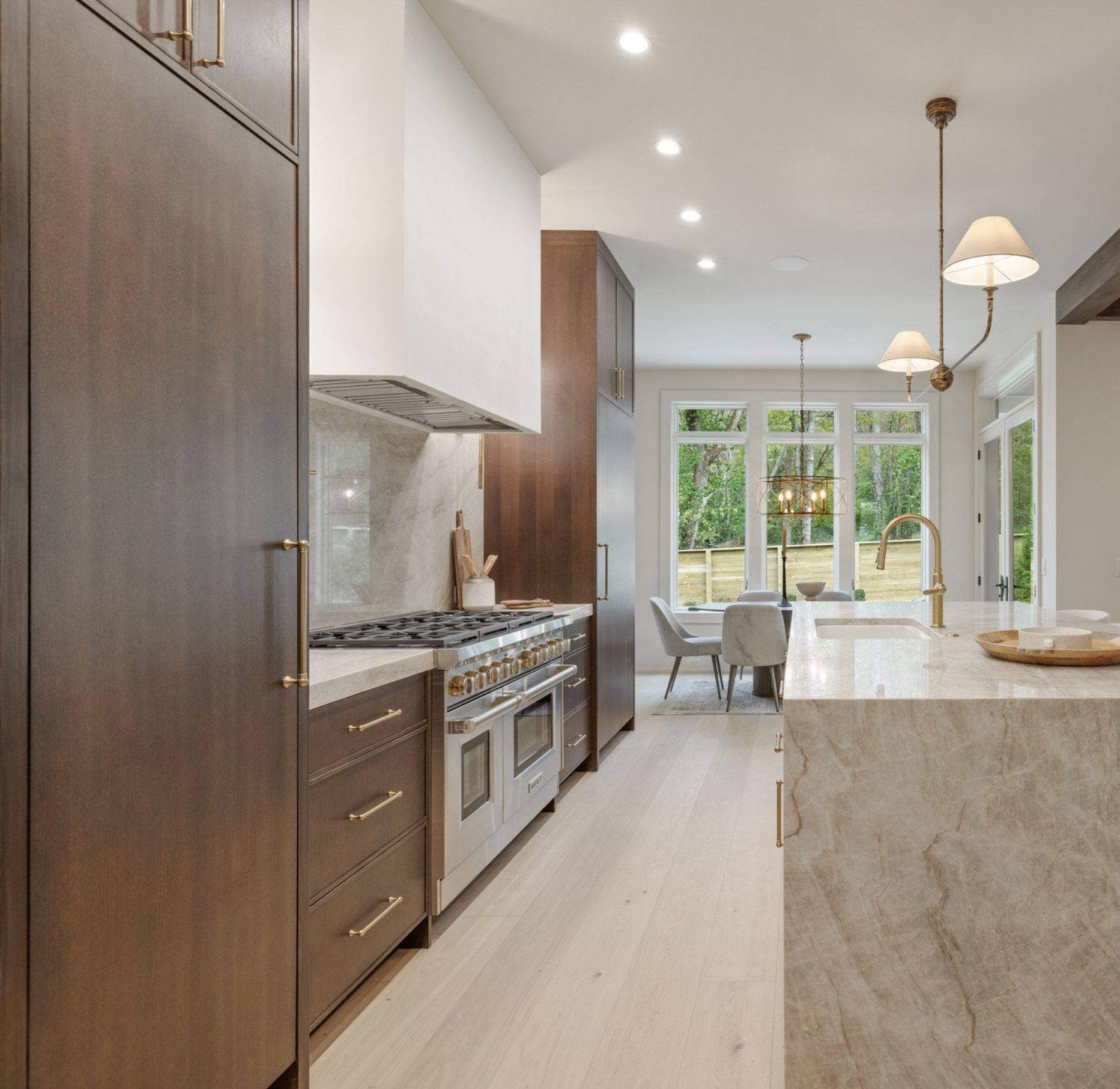 Modern kitchen with dark wood cabinets, stainless steel appliances, and a marble countertop.