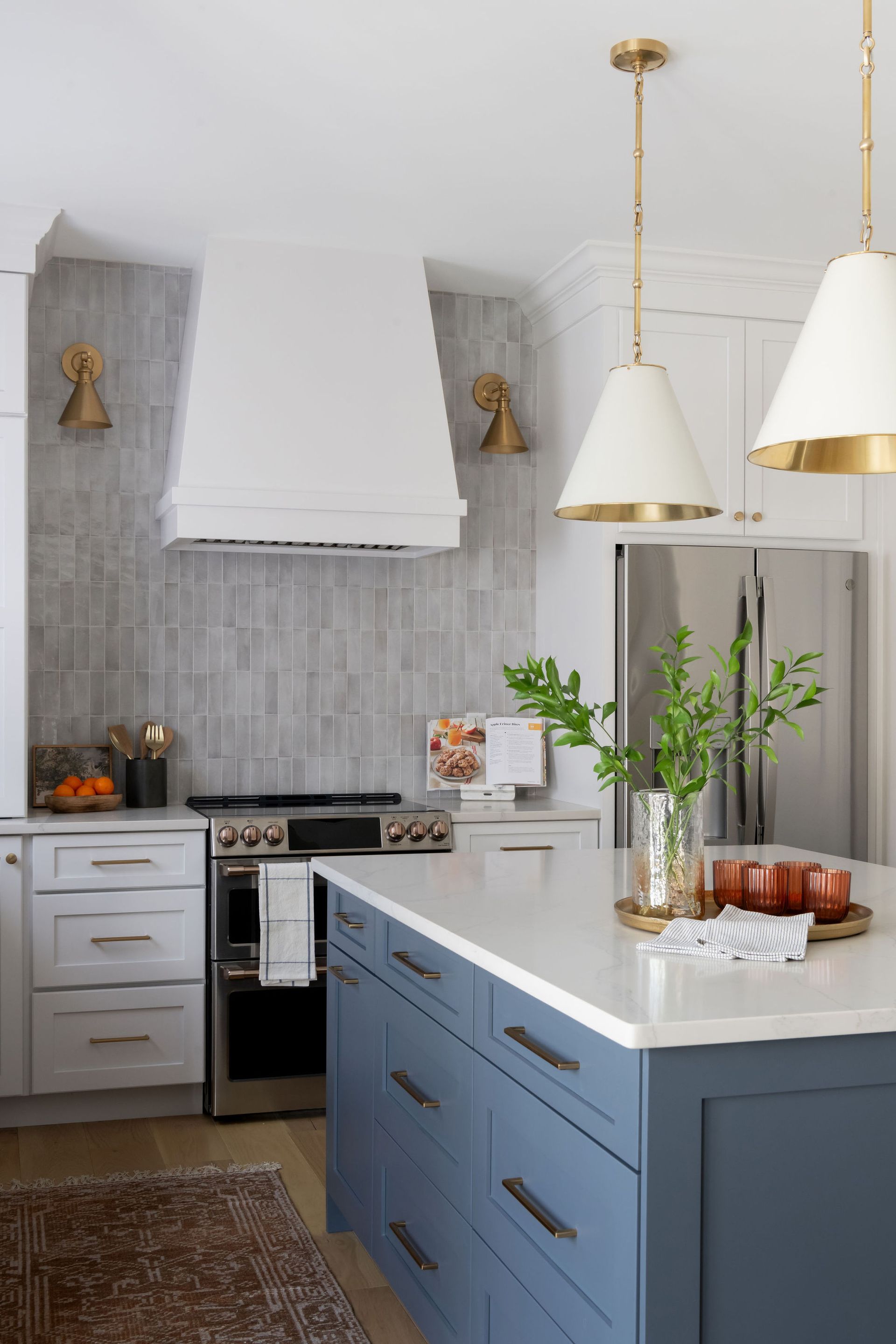 Stylish kitchen with blue island, white countertops, stainless steel appliances, and gold accents.