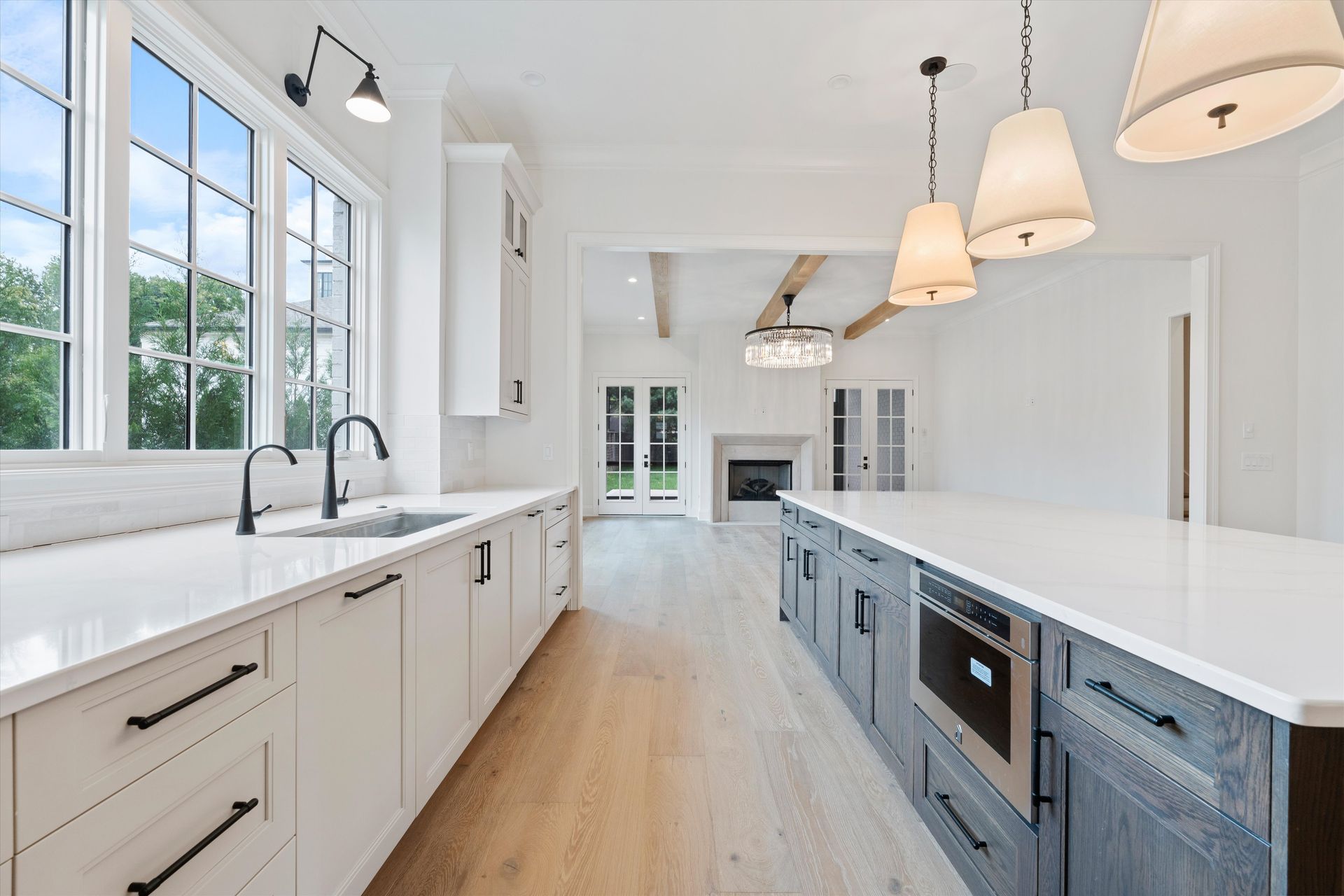 Modern kitchen with white cabinets, gray island, and view of a living area.