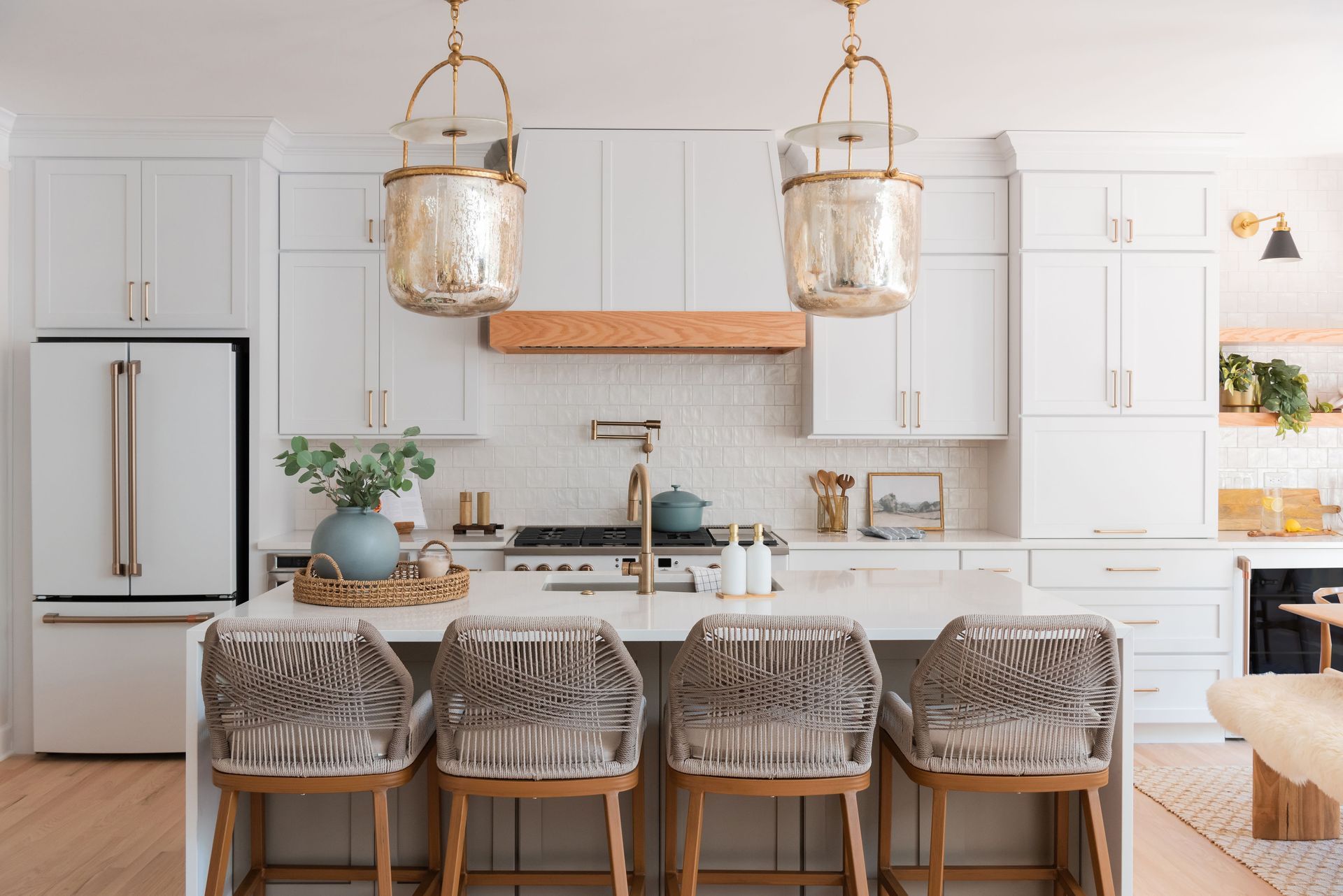 White kitchen with island seating, pendant lights, and stainless steel appliances.