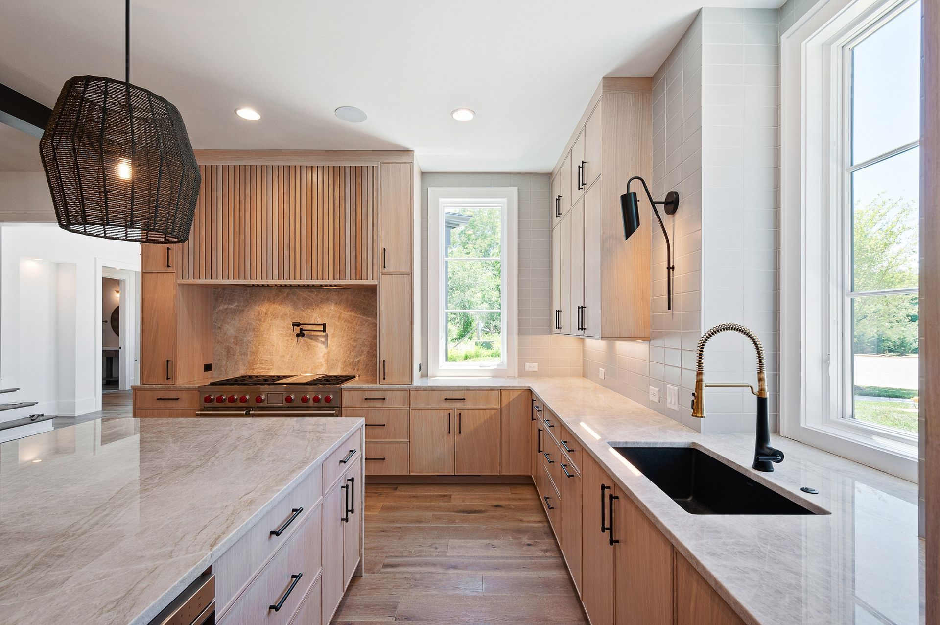 Modern kitchen with light wood cabinets, granite countertops, and a black sink.