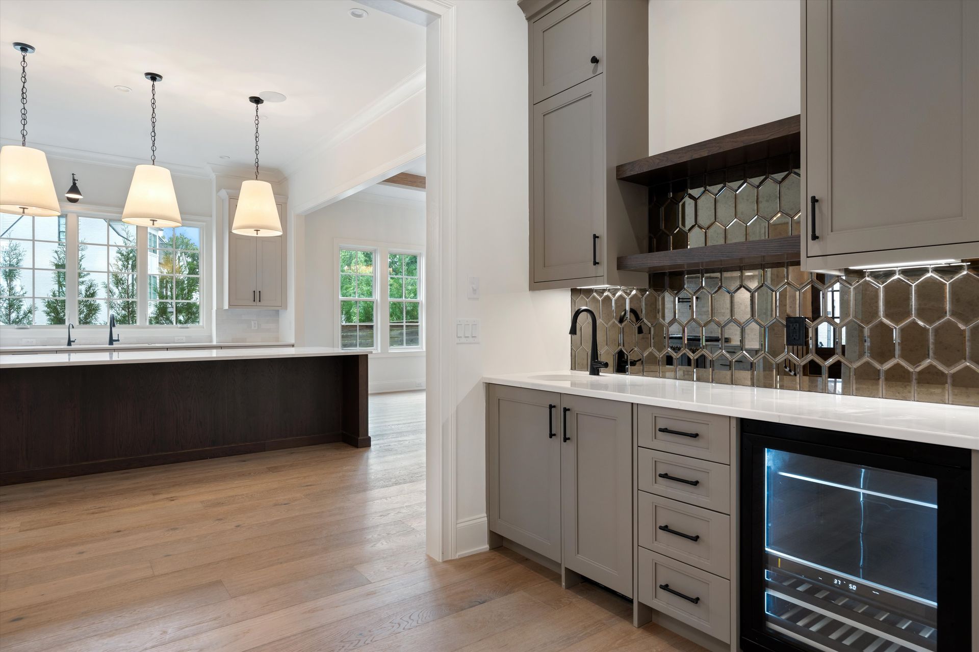 Kitchen with gray cabinetry, a wine fridge, and a reflective backsplash.
