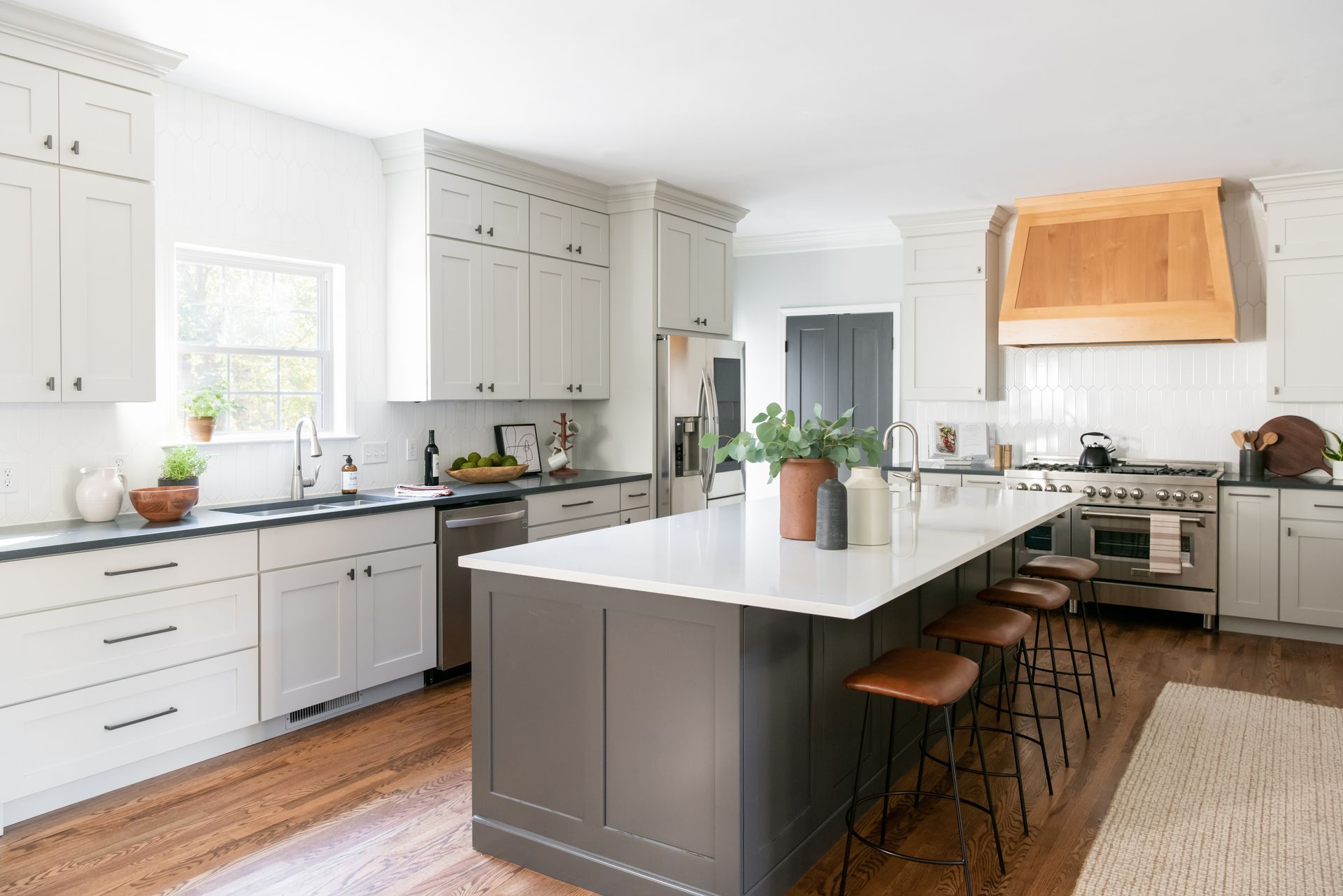 Modern kitchen with white cabinets, dark gray island, and wood floors.