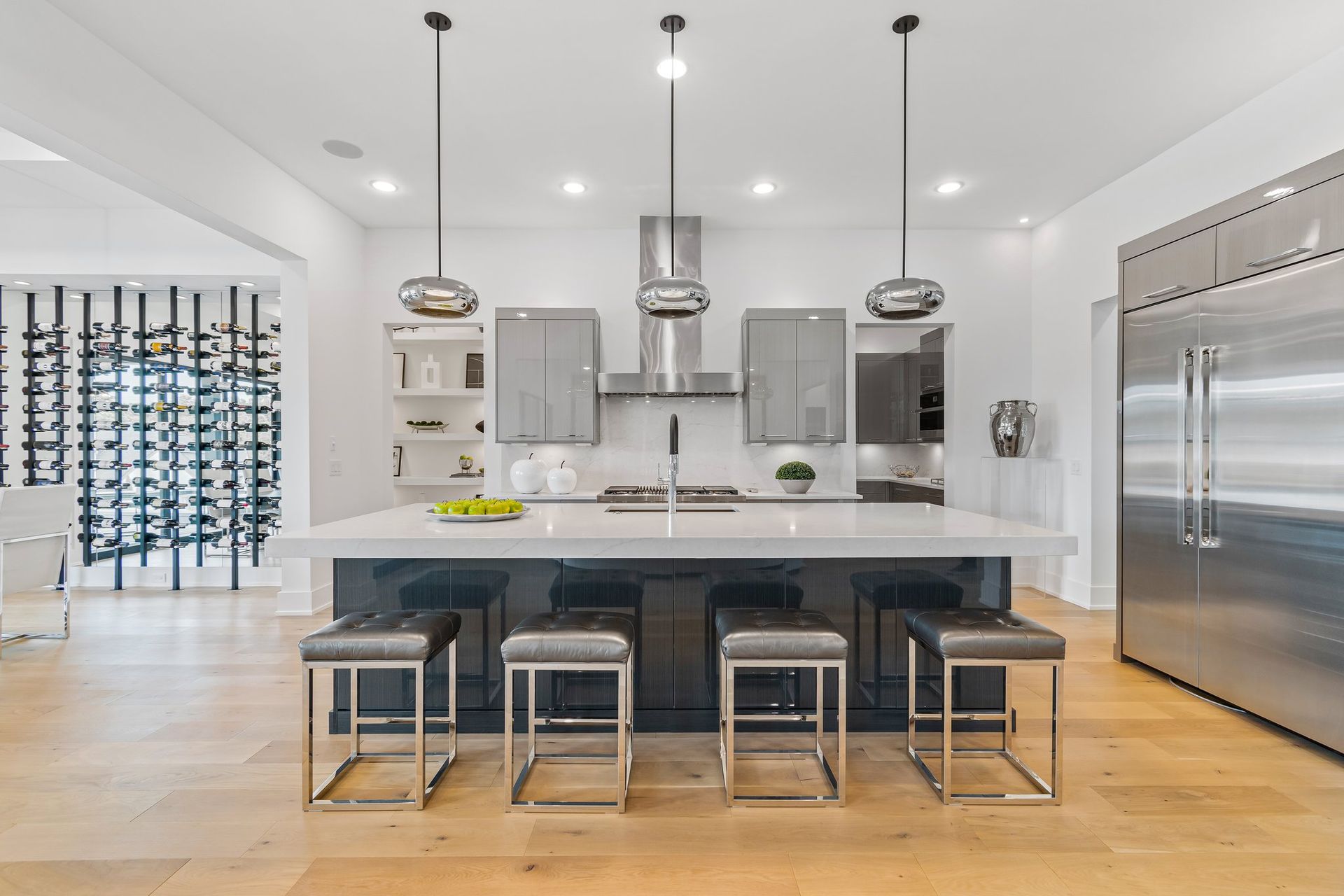 Modern kitchen with island, stainless steel appliances, pendant lights, and bar stools.
