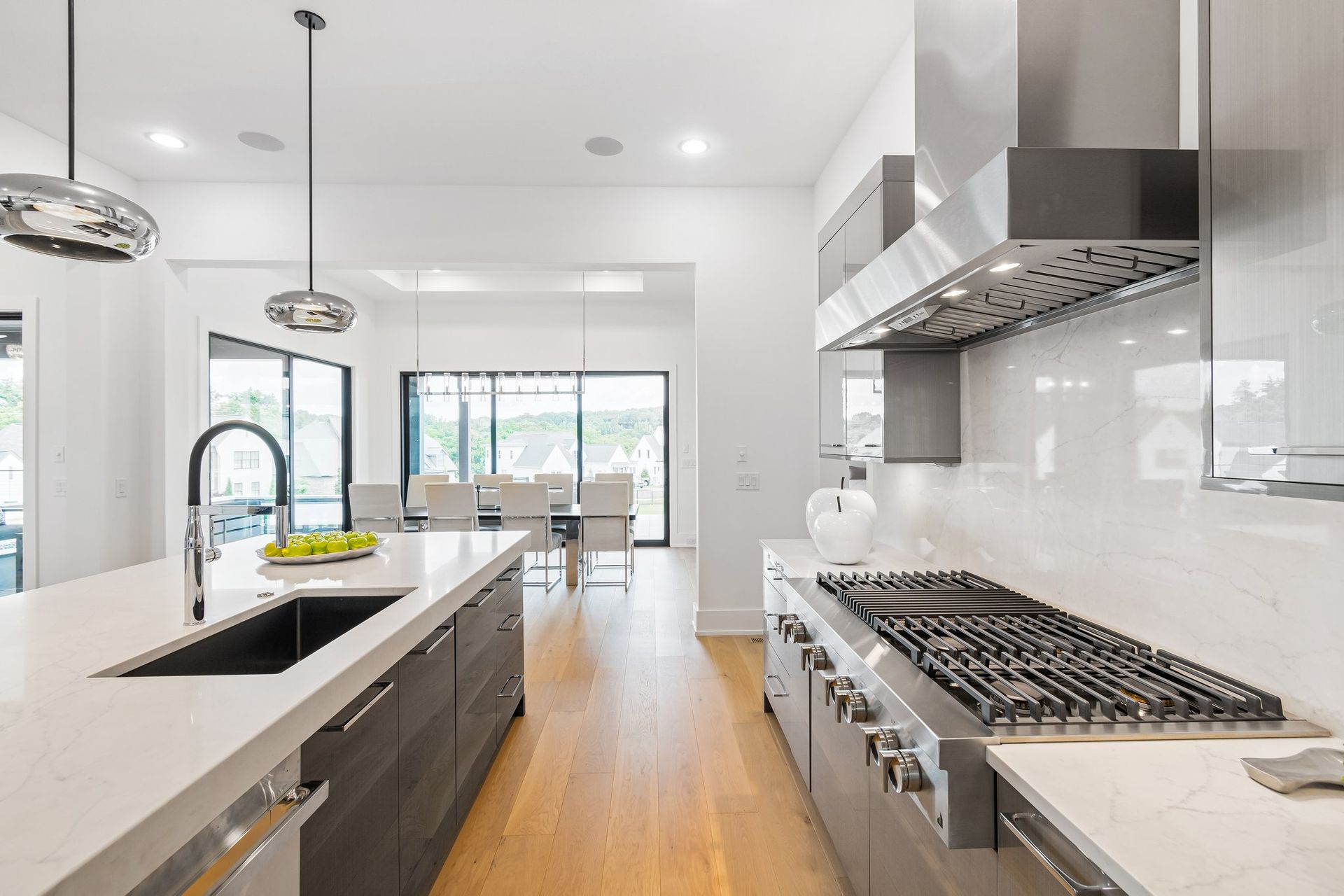 Modern kitchen with stainless steel appliances, light wood floors, and a large island.