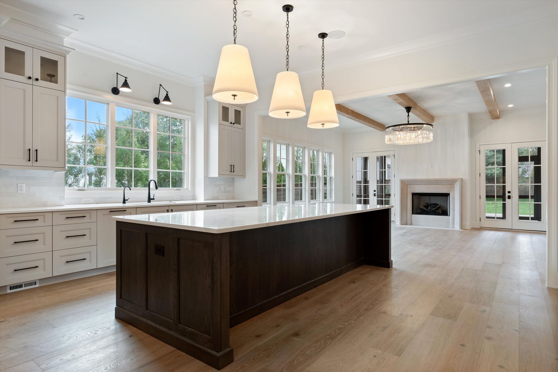 Spacious kitchen with a large dark wood island, white cabinets, and three hanging pendant lights.