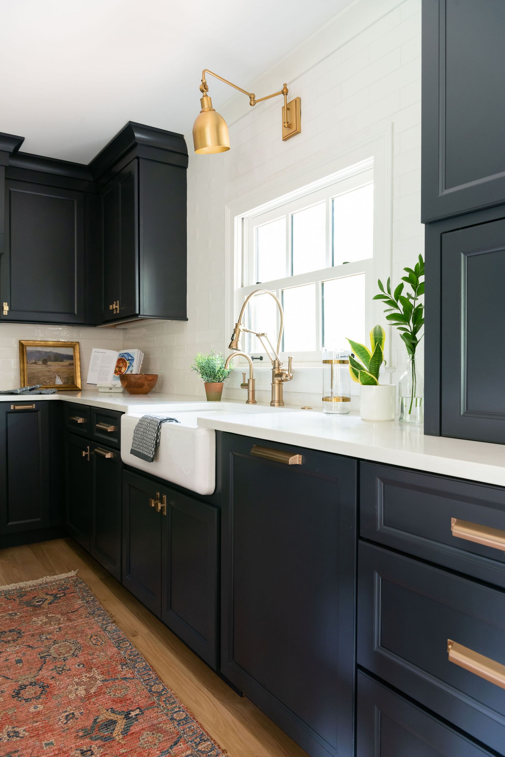 Kitchen with dark blue cabinets, white countertops, and gold fixtures.