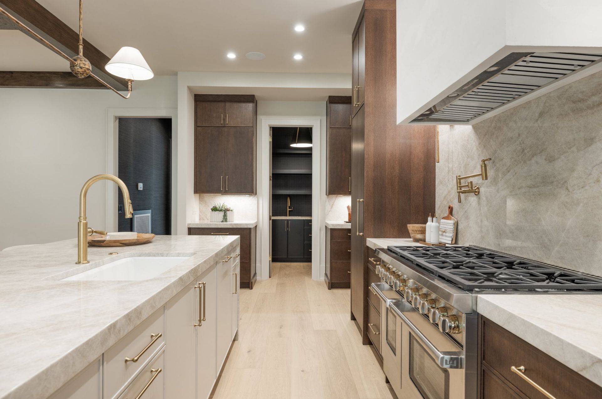 Modern kitchen with island, range, dark cabinets, and light wood floor.
