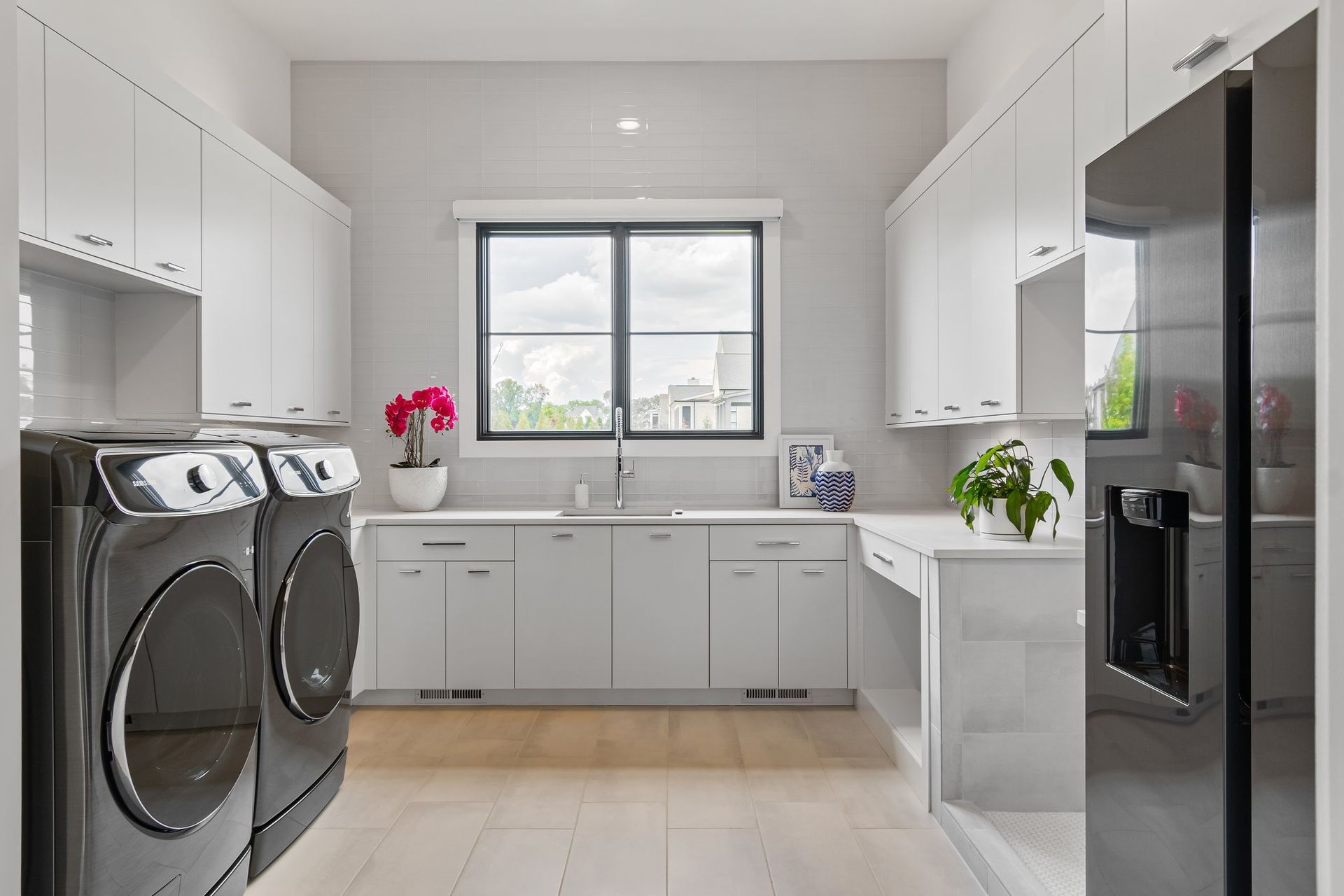Laundry room with white cabinets, appliances, and light wood floor.