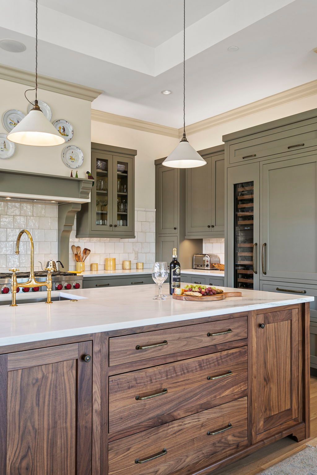 Elegant kitchen with a wooden island, sage green cabinets, and white countertops.