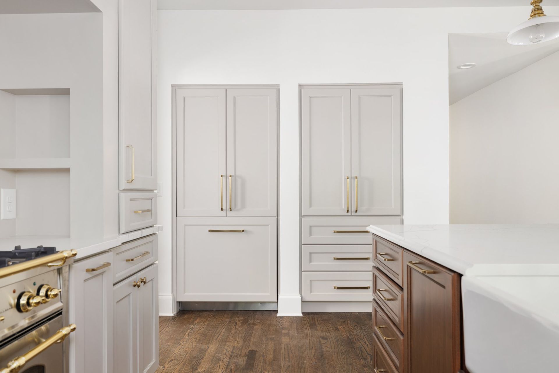 Kitchen with light gray cabinets, gold hardware, and dark wood floors.