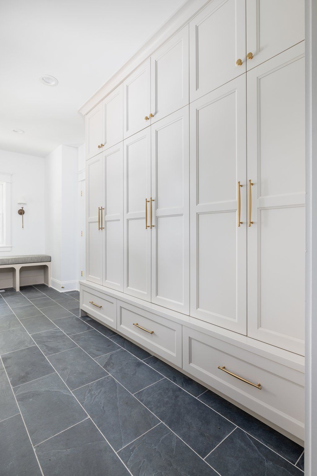 White storage cabinets with gold handles and gray tiled floor in a room.