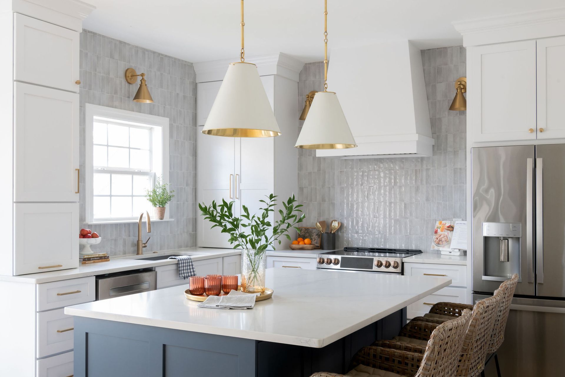 Modern white kitchen with island, pendant lights, and stainless steel appliances.