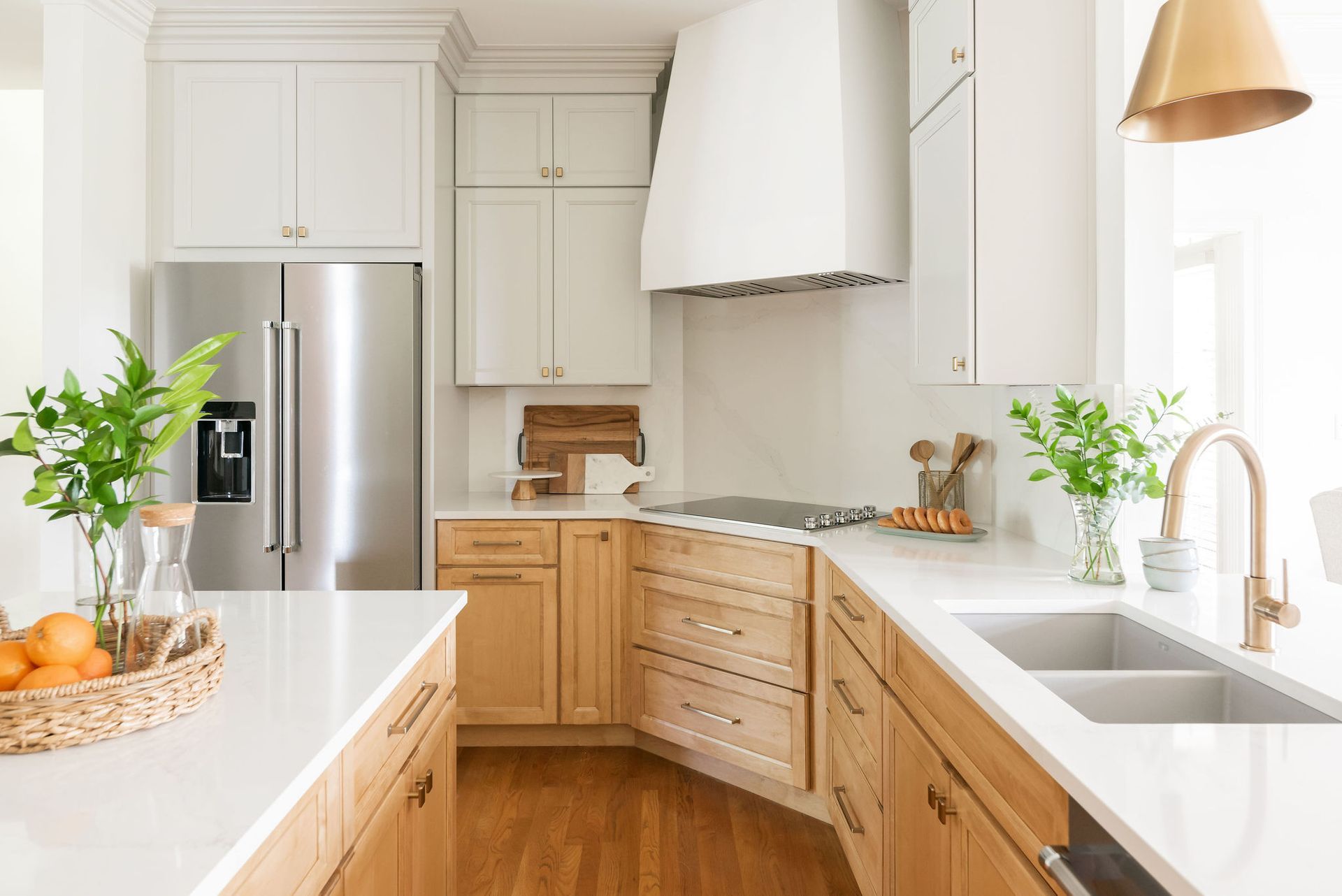 Bright kitchen with white and natural wood cabinets, stainless steel appliances, and quartz countertops.