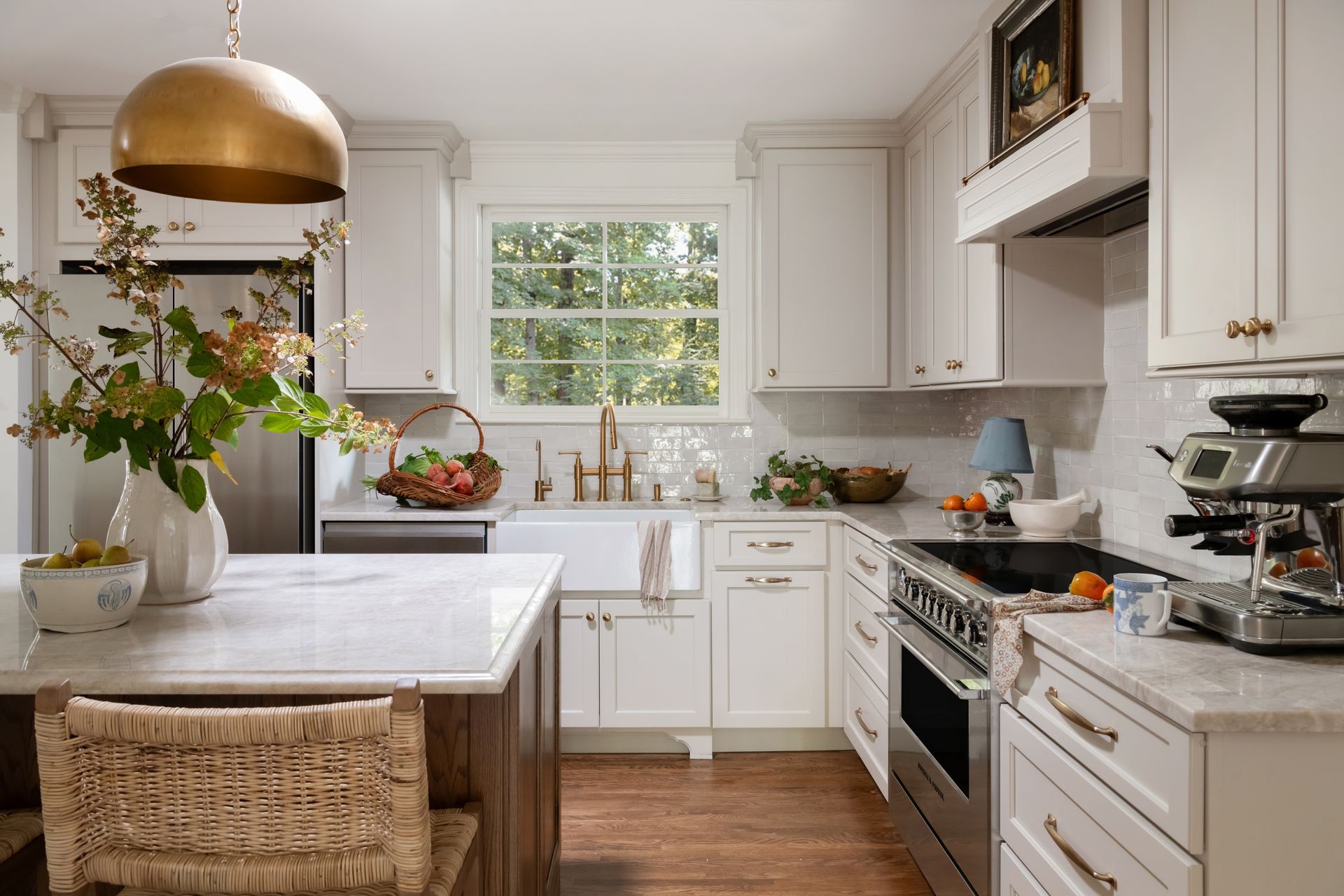 Bright, white kitchen with island, stainless appliances, and gold accents.