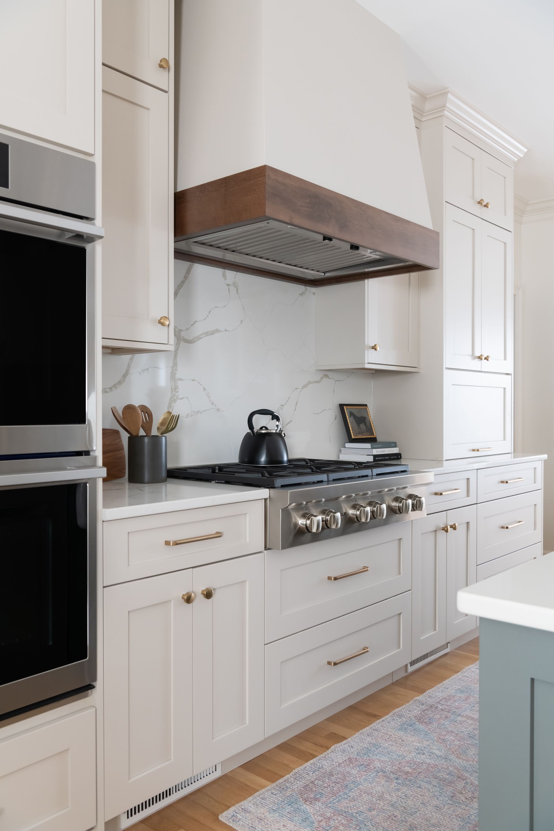 Kitchen with white cabinets, stainless steel appliances, and a wooden range hood.