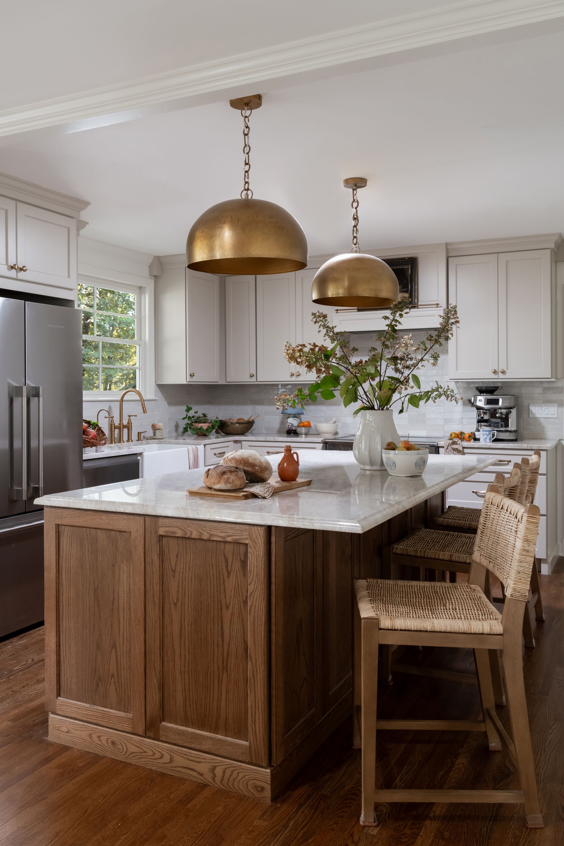 Kitchen with white cabinets, wood island, gold pendant lights, and bar stools.
