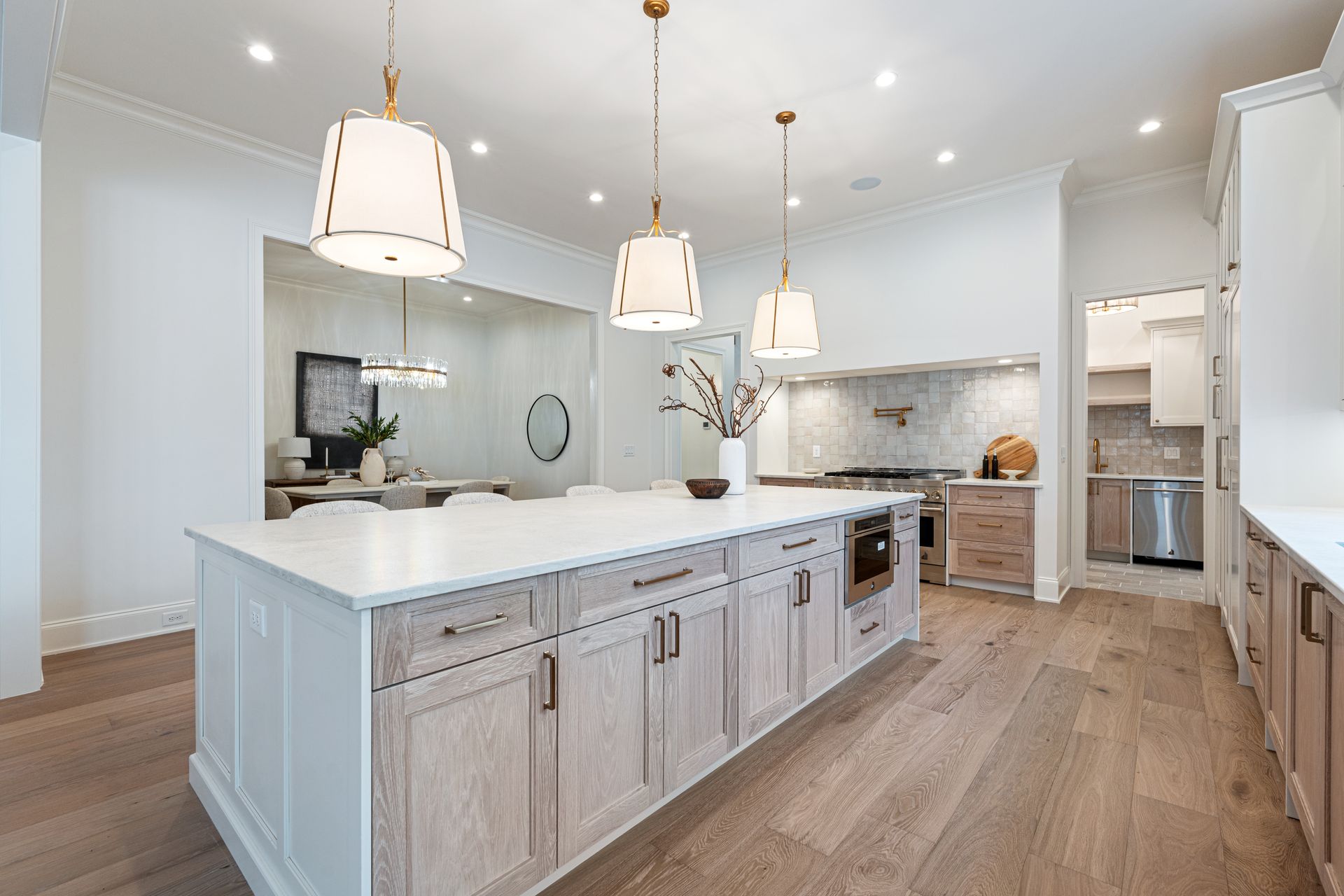Modern kitchen with island, pendant lights, light wood cabinets, and hardwood floors.