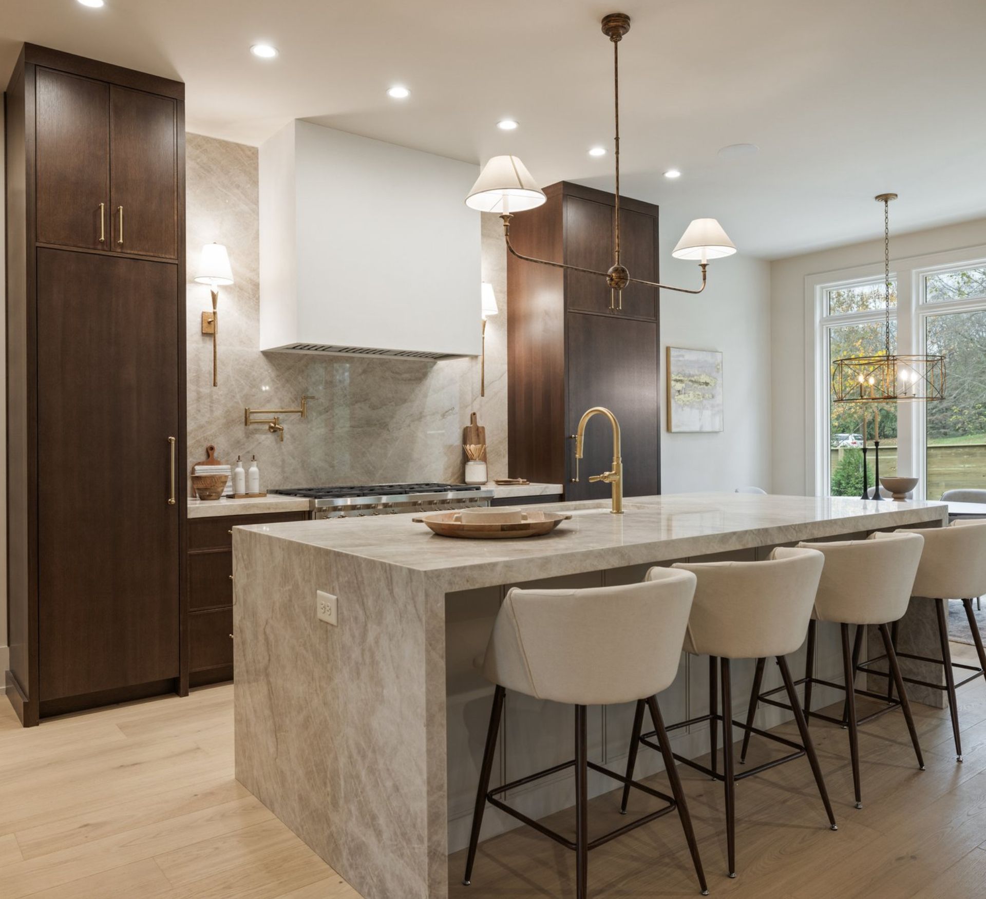Modern kitchen with island seating, dark wood cabinets, and light stone countertop.