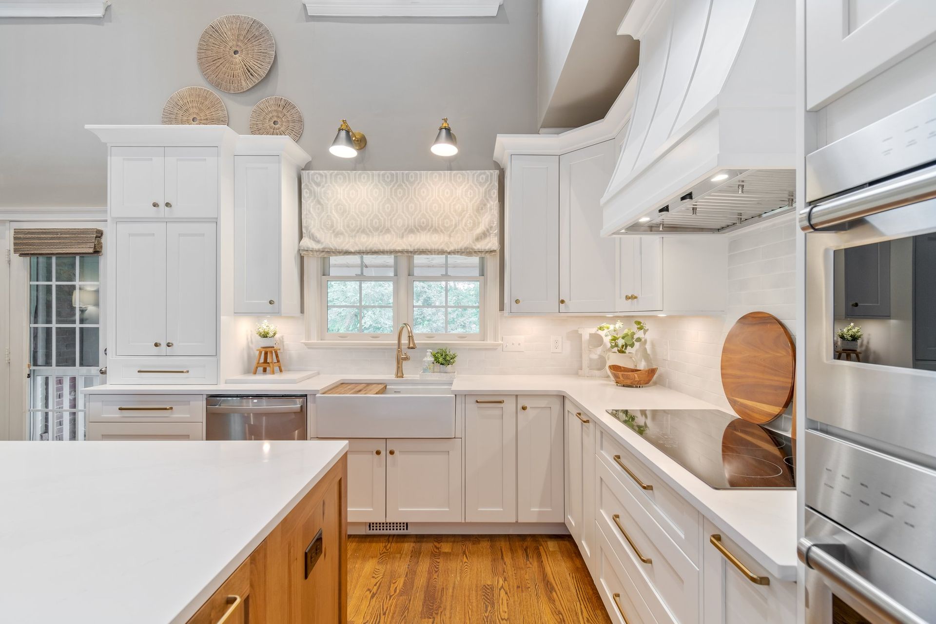 White kitchen with wood floors, island, cabinets, and appliances.
