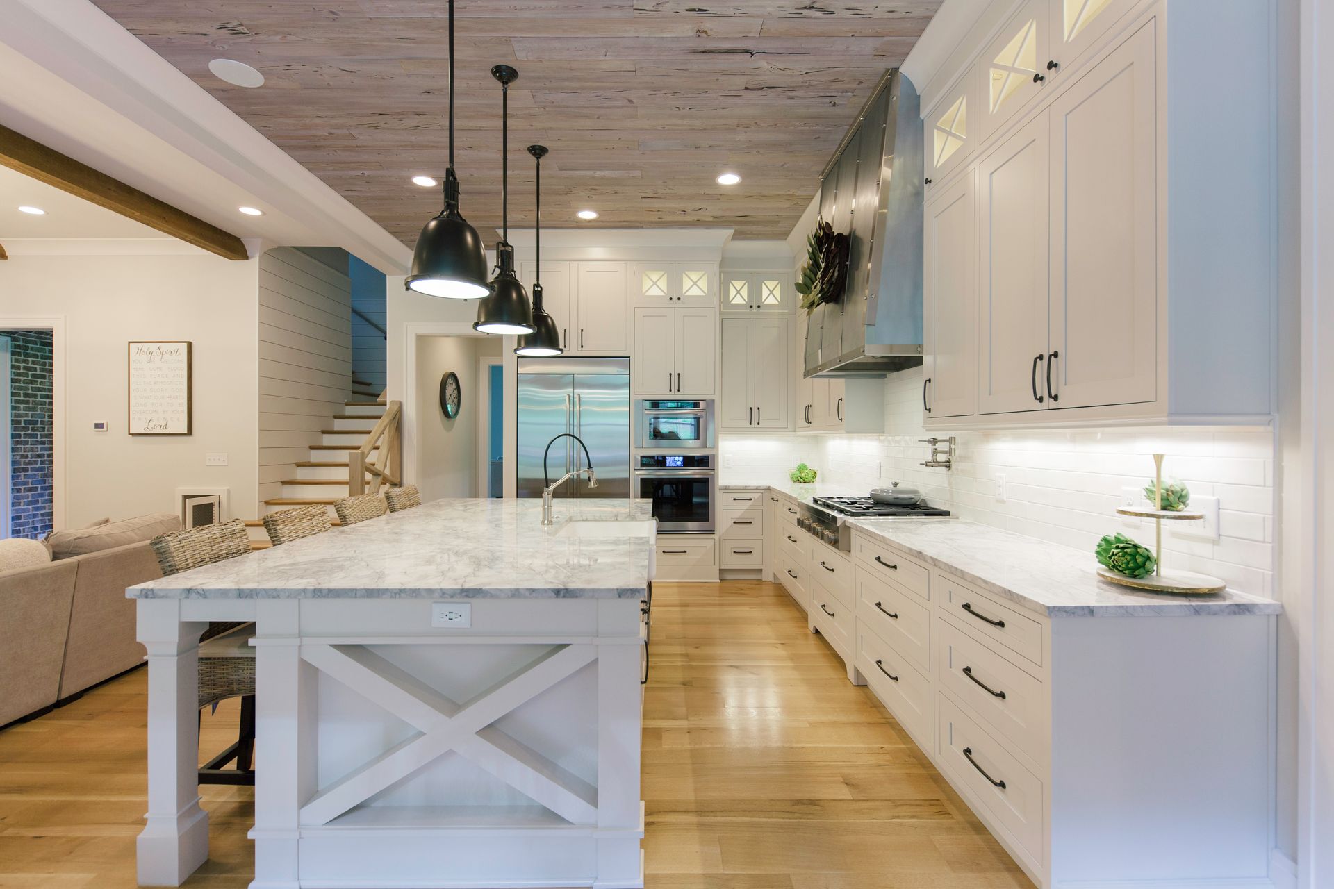 Modern kitchen with white cabinets, island, wooden ceiling, and pendant lights.