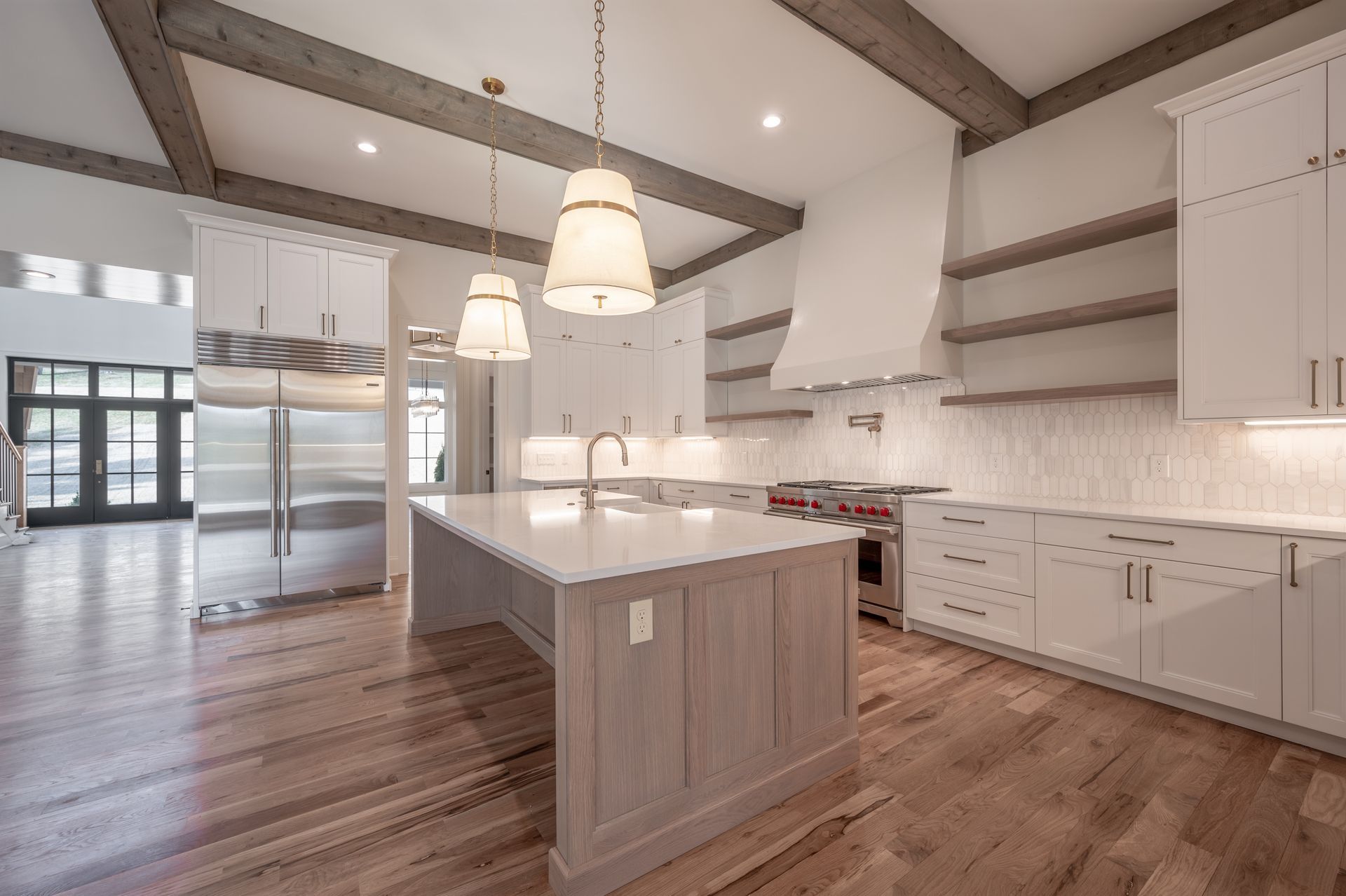 Modern kitchen with white cabinets, wood island, and exposed beams; stainless steel appliances.