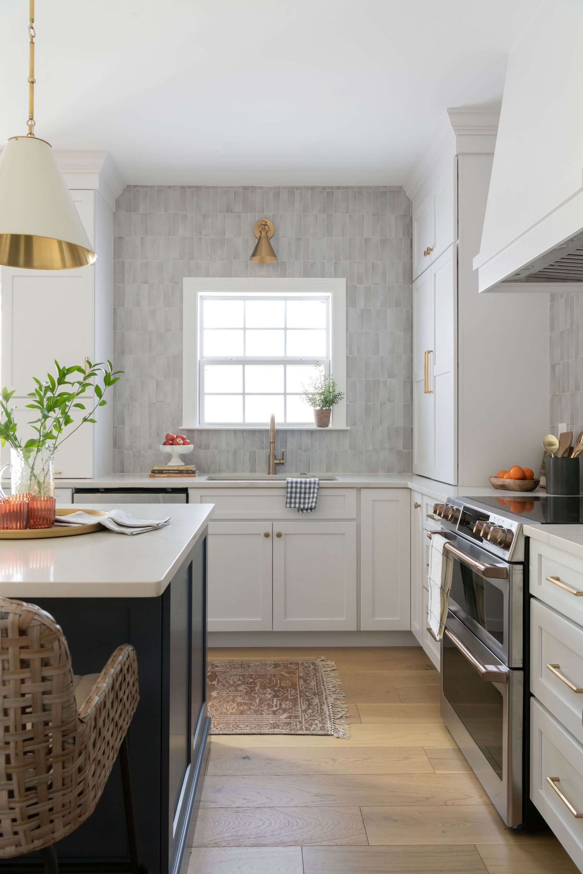 Kitchen with white cabinets, island, stainless steel oven, and wooden floor.