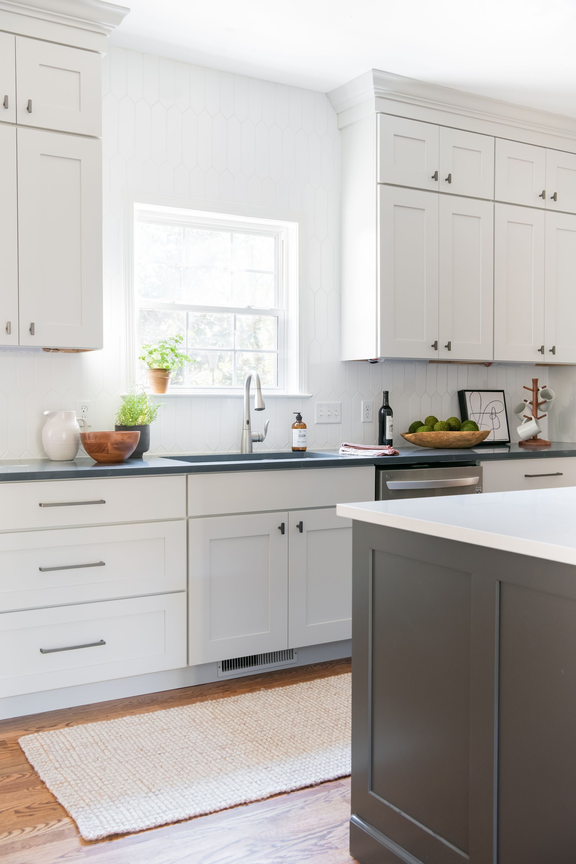 White kitchen with gray cabinets, black countertops, and wooden floors.