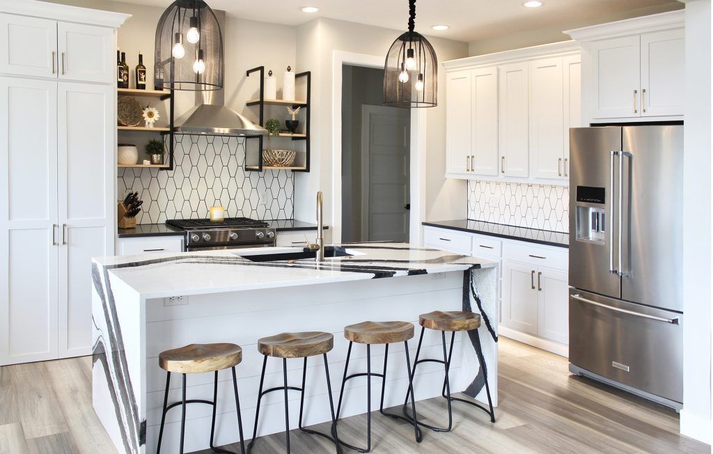Modern white kitchen with a stainless steel refrigerator and island with stools.