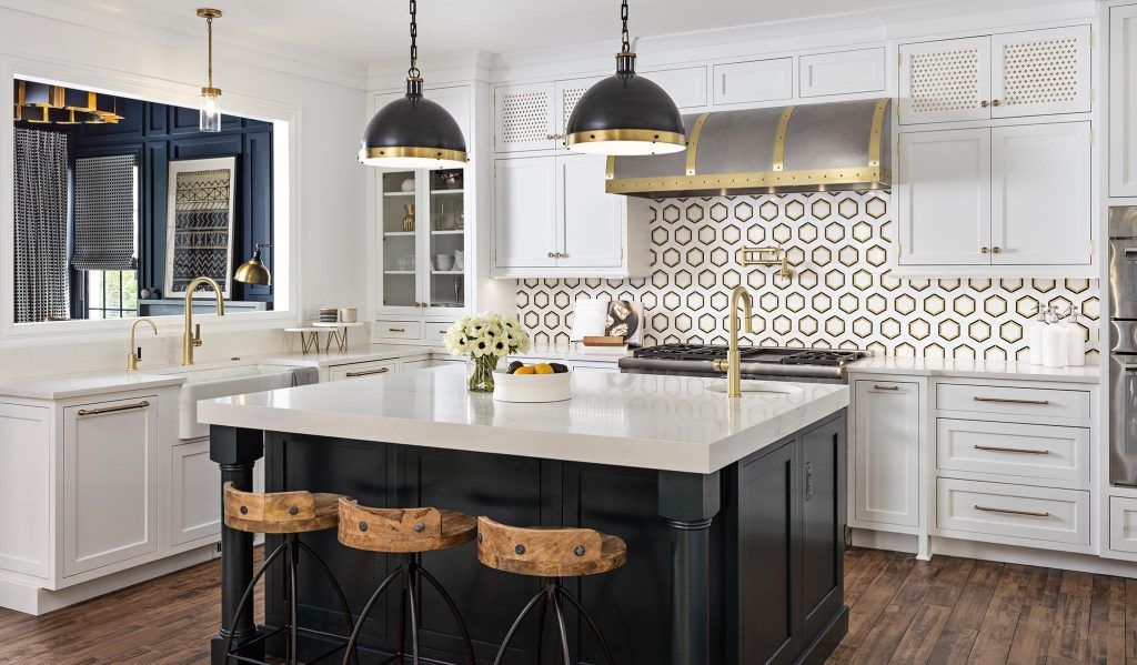 Elegant kitchen with white cabinets, black island, and gold accents.